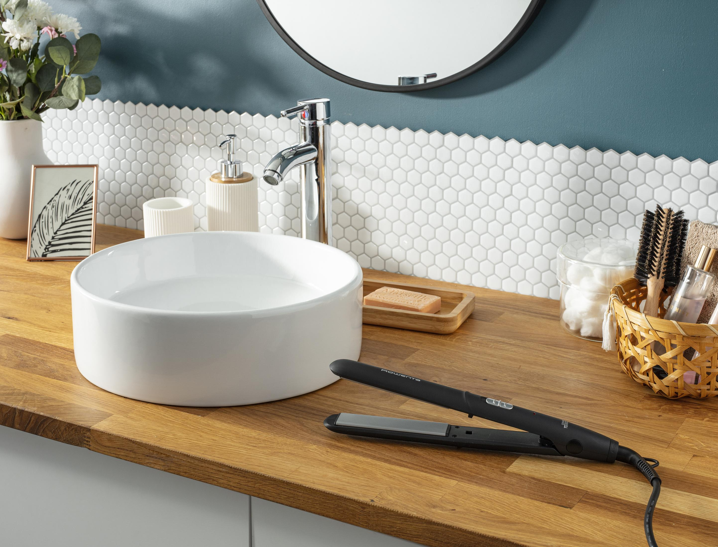 Łazienka z umywalką i prostownicą do włosów na drewnianym blacie.