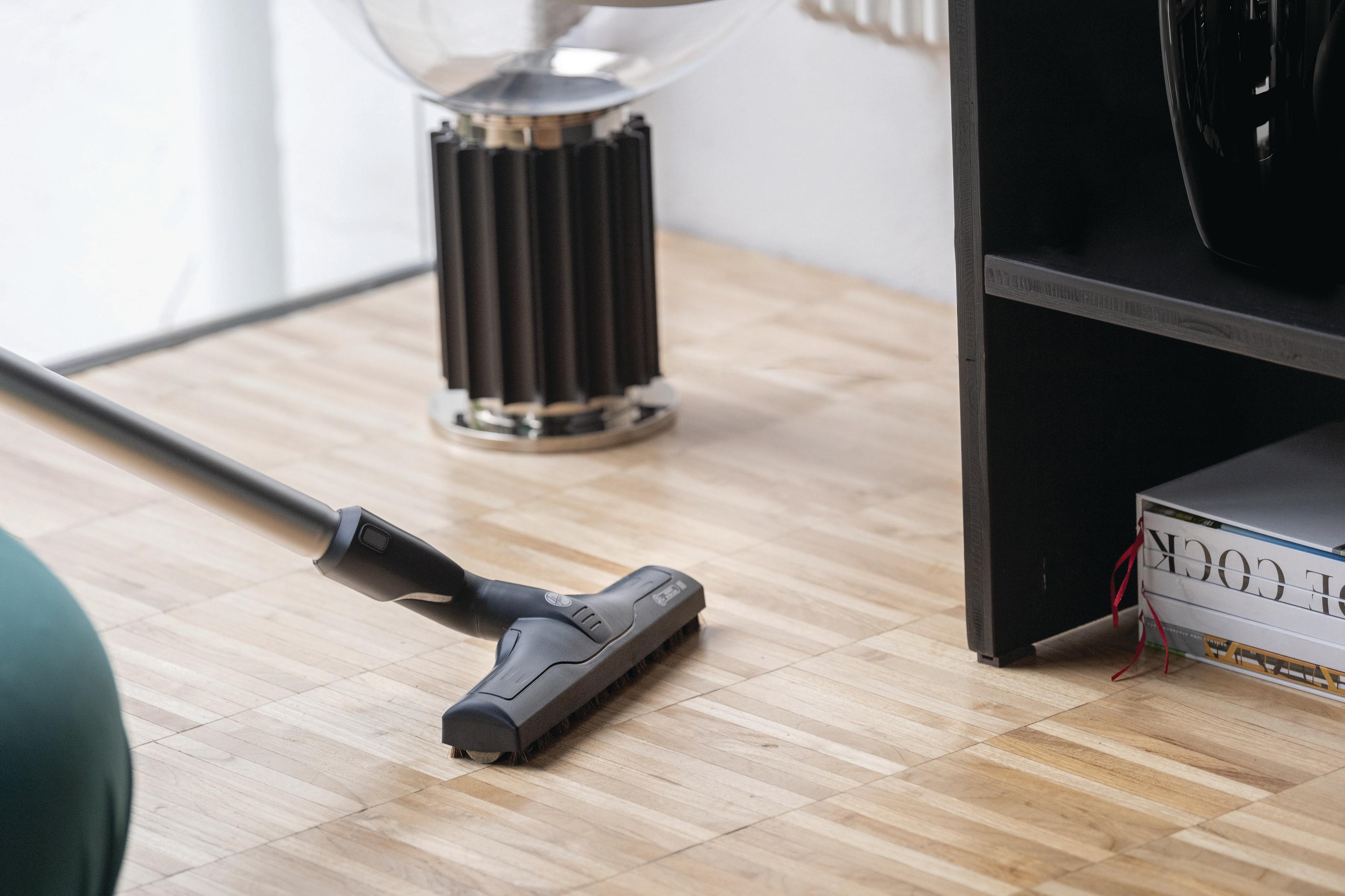 Głowica odkurzacza czyszcząca drewnianą podłogę, widok z bliska.