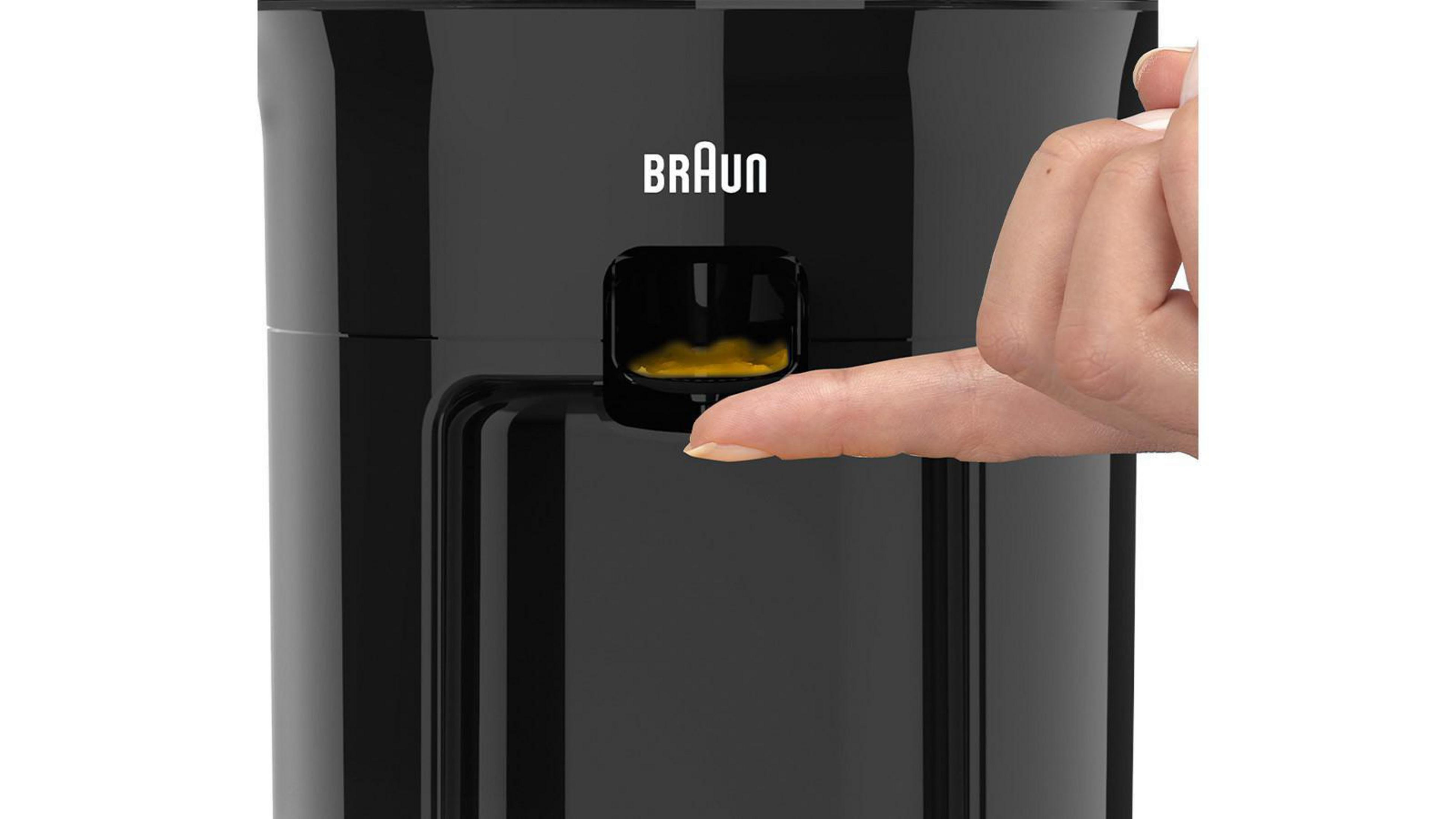 Zbliżenie czarnego urządzenia Braun. Palec naciska żółty przycisk.