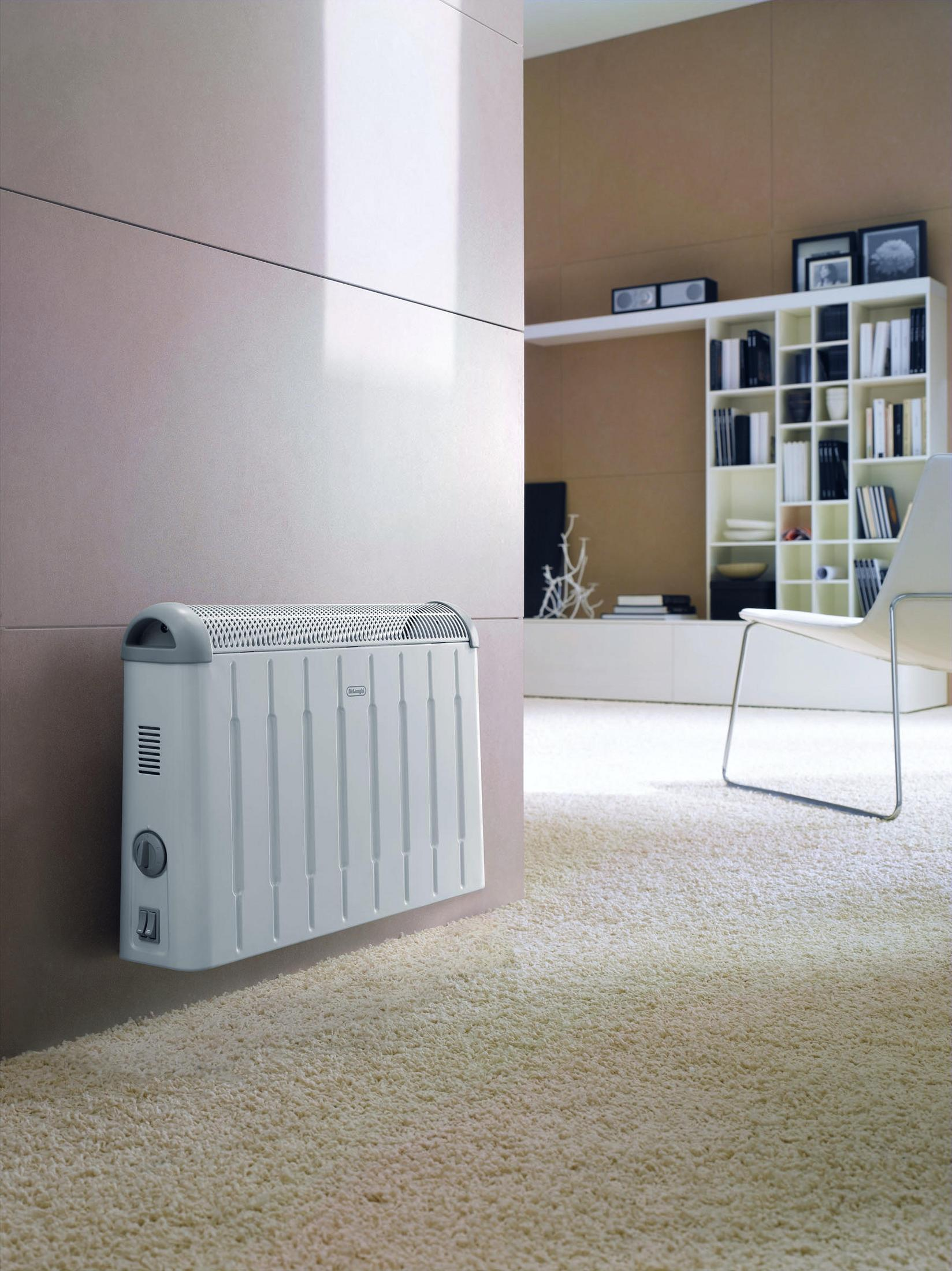 Weißer Elektroheizer an einer beigen Wand, mit weißem flauschigem Teppich. Modernes Interieur.