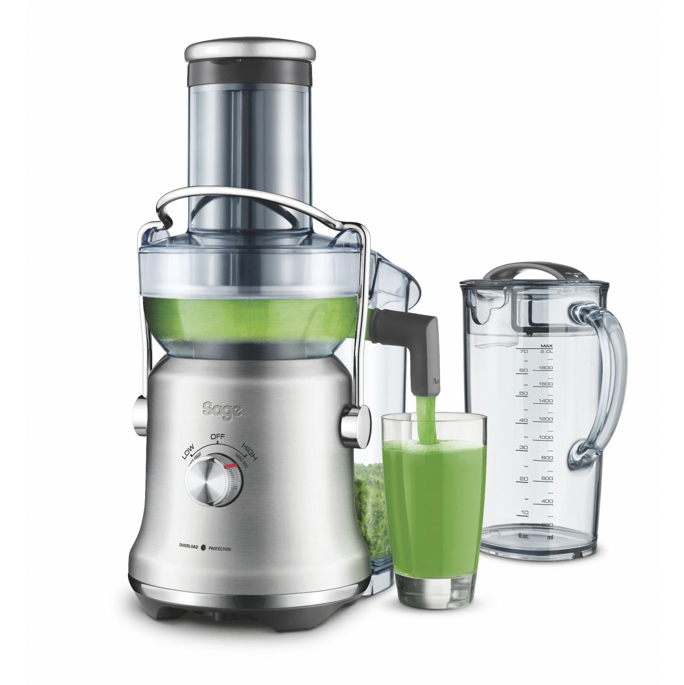 Spremiagrumi con succo verde versato in un bicchiere. Un contenitore trasparente e una brocca graduata sono a lato.