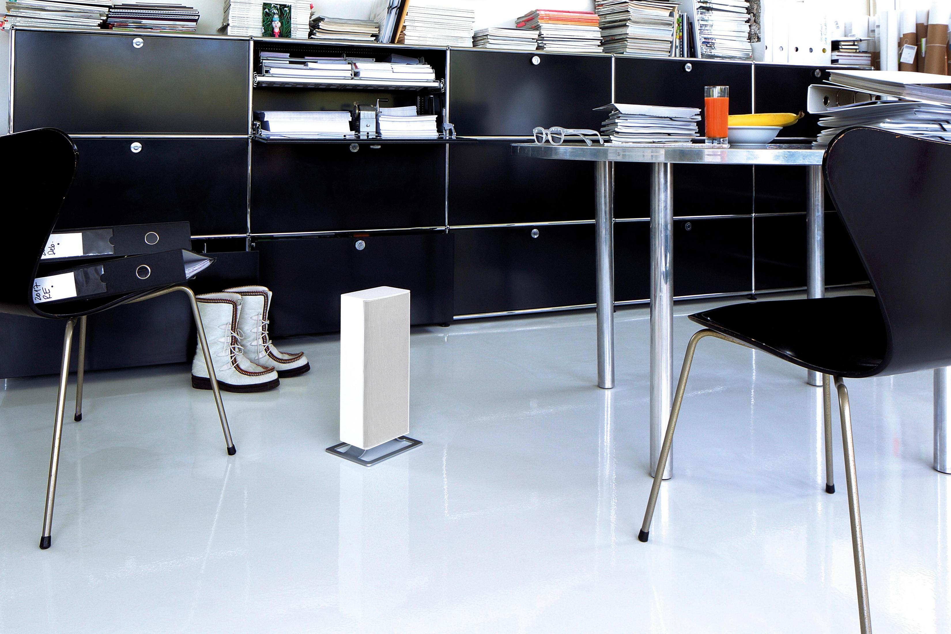 Scena biurowa z białą podłogą, czarnymi meblami i białym oczyszczaczem powietrza. Stół jest nakryty.