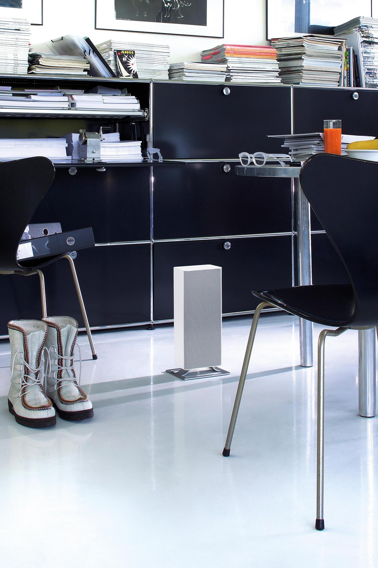 Nowoczesna przestrzeń biurowa z czarnymi meblami, białymi ścianami i białą podłogą.