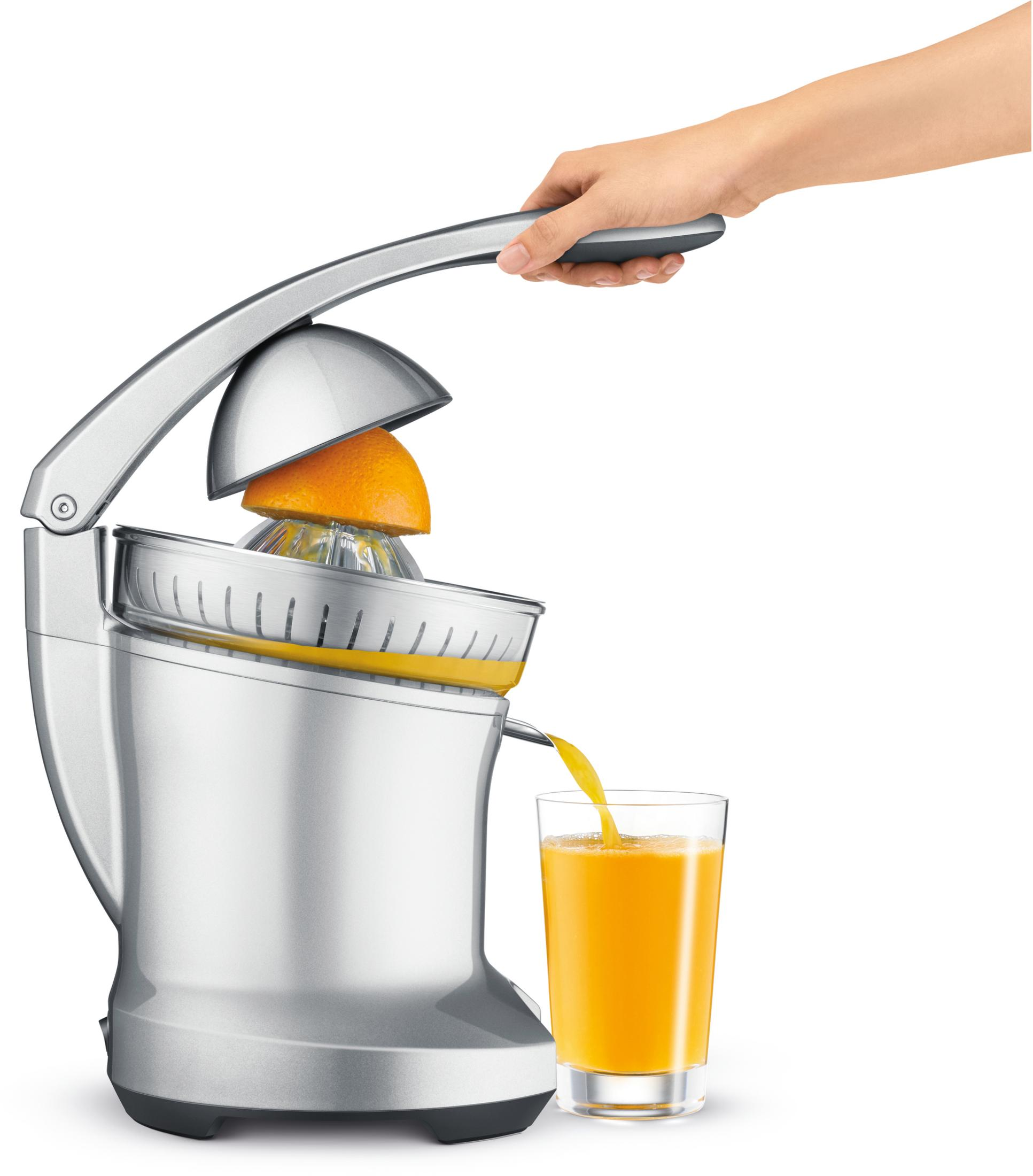 Una persona exprimiendo una naranja con un exprimidor plateado, vertiendo zumo de naranja en un vaso.