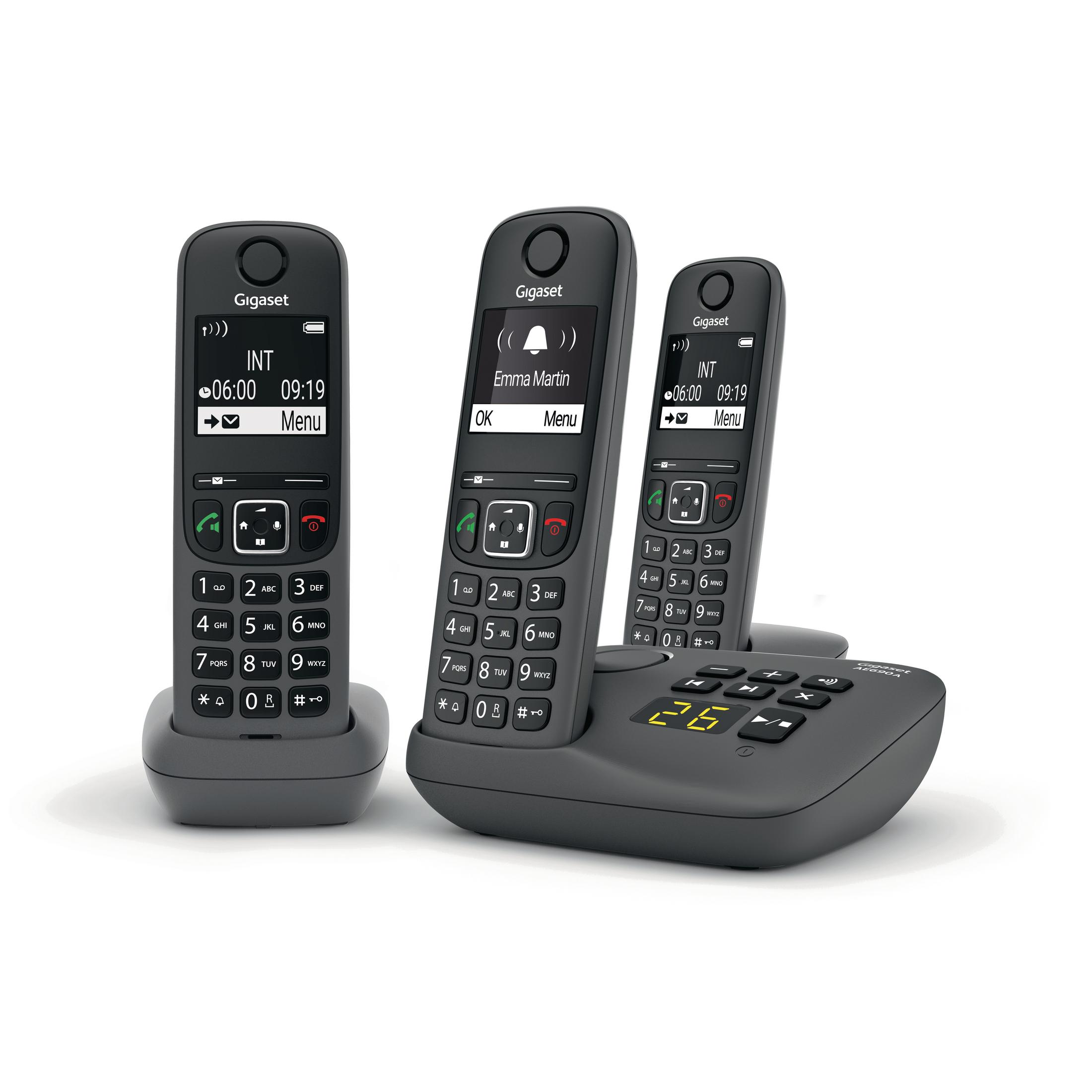 Tre telefoni cordless Gigaset grigi su una base di ricarica. I telefoni hanno schermi e tastiere.