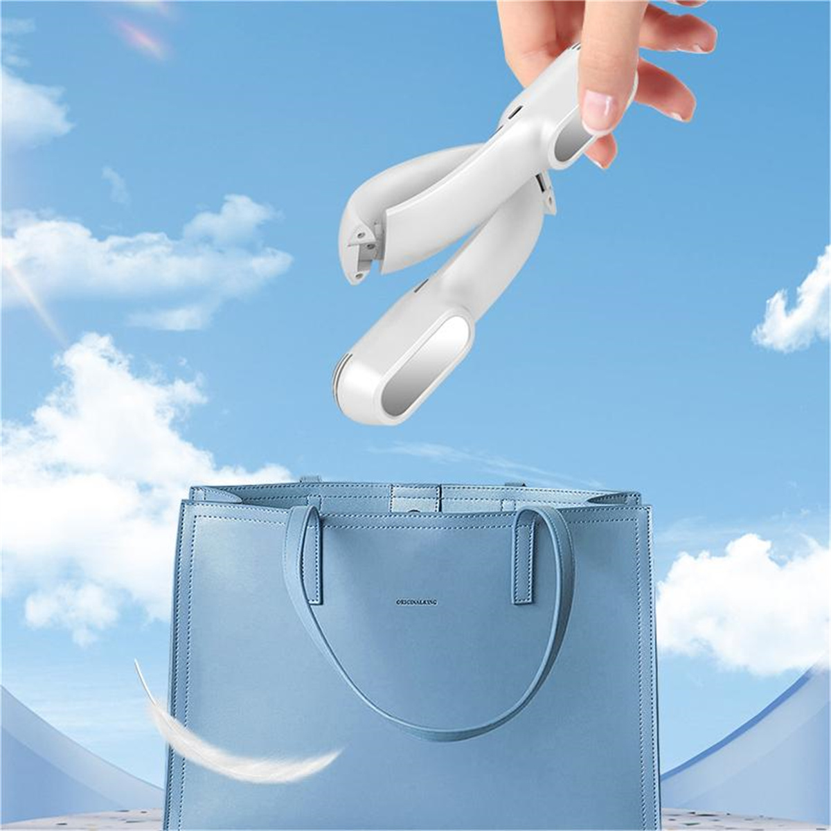Eine Hand hält einen weißen tragbaren Ventilator über einer blauen Handtasche.