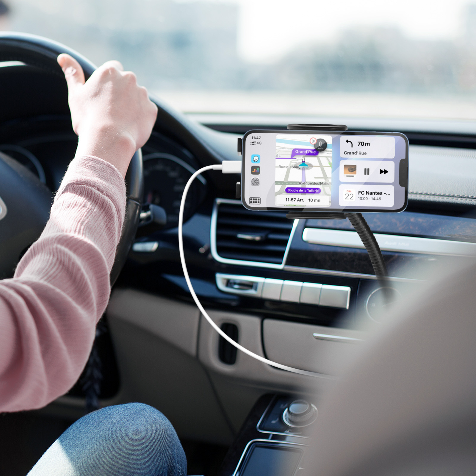 Hände einer Person am Lenkrad. Telefon auf Halter mit Karte.