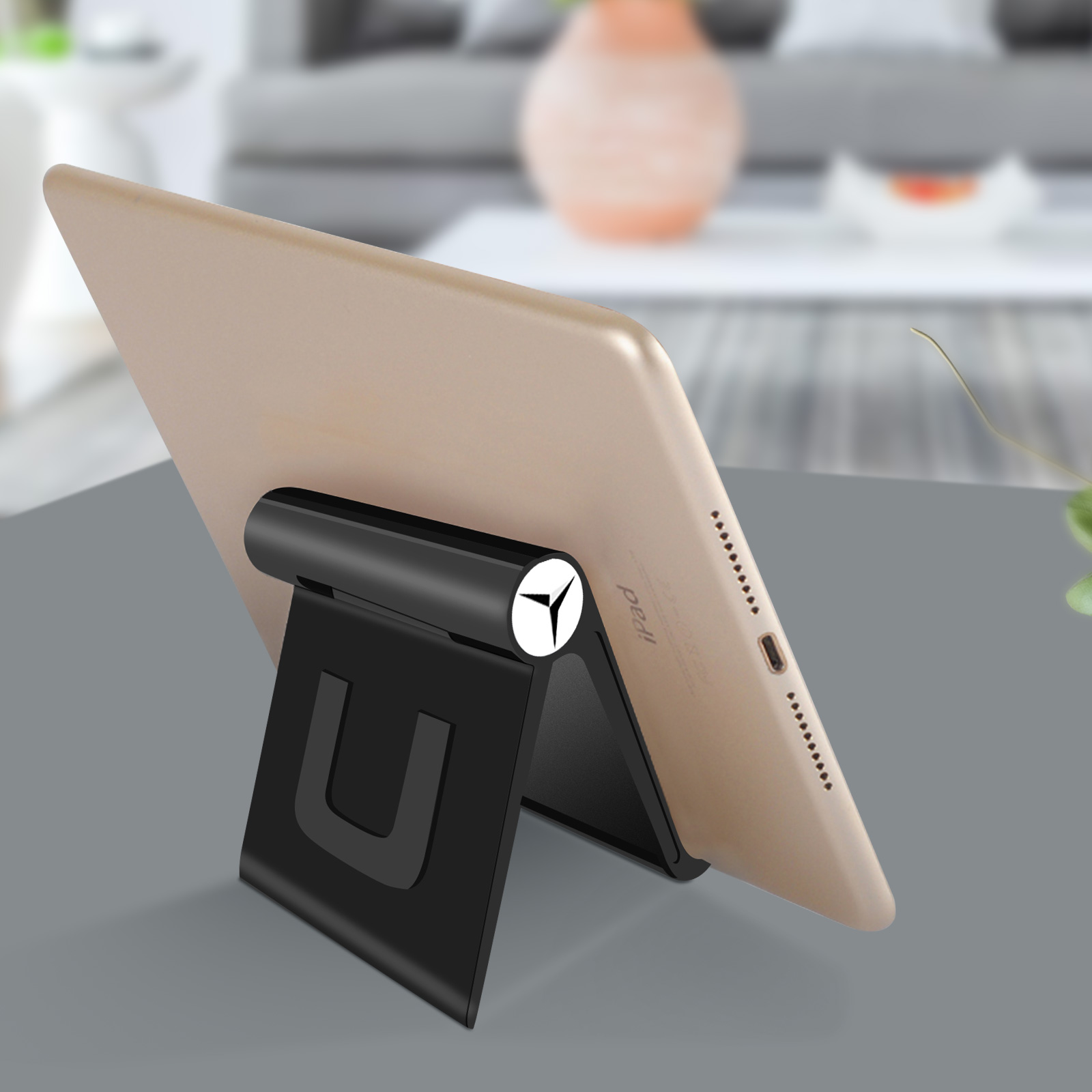 Un tablet in un supporto nero su una superficie grigia. Il tablet è inclinato, mostrando lo schermo.
