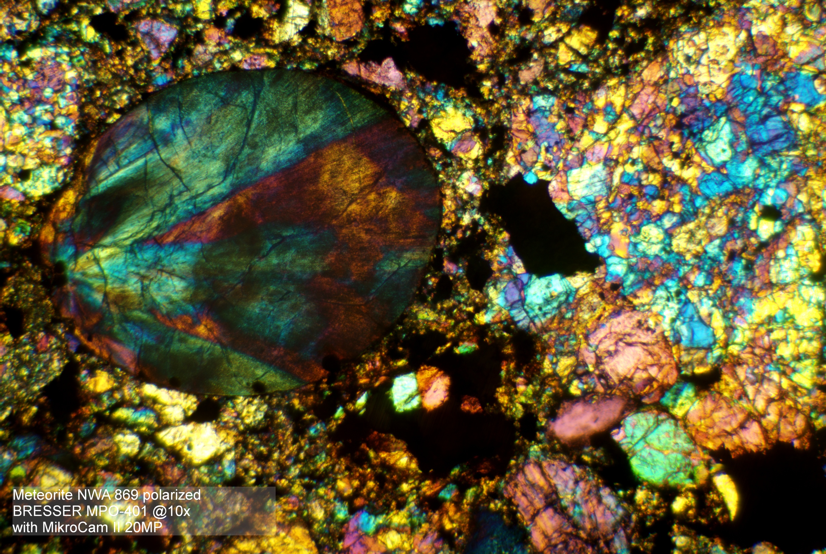 Una vista microscópica de un meteorito. Muestra estructuras minerales coloridas bajo luz polarizada.