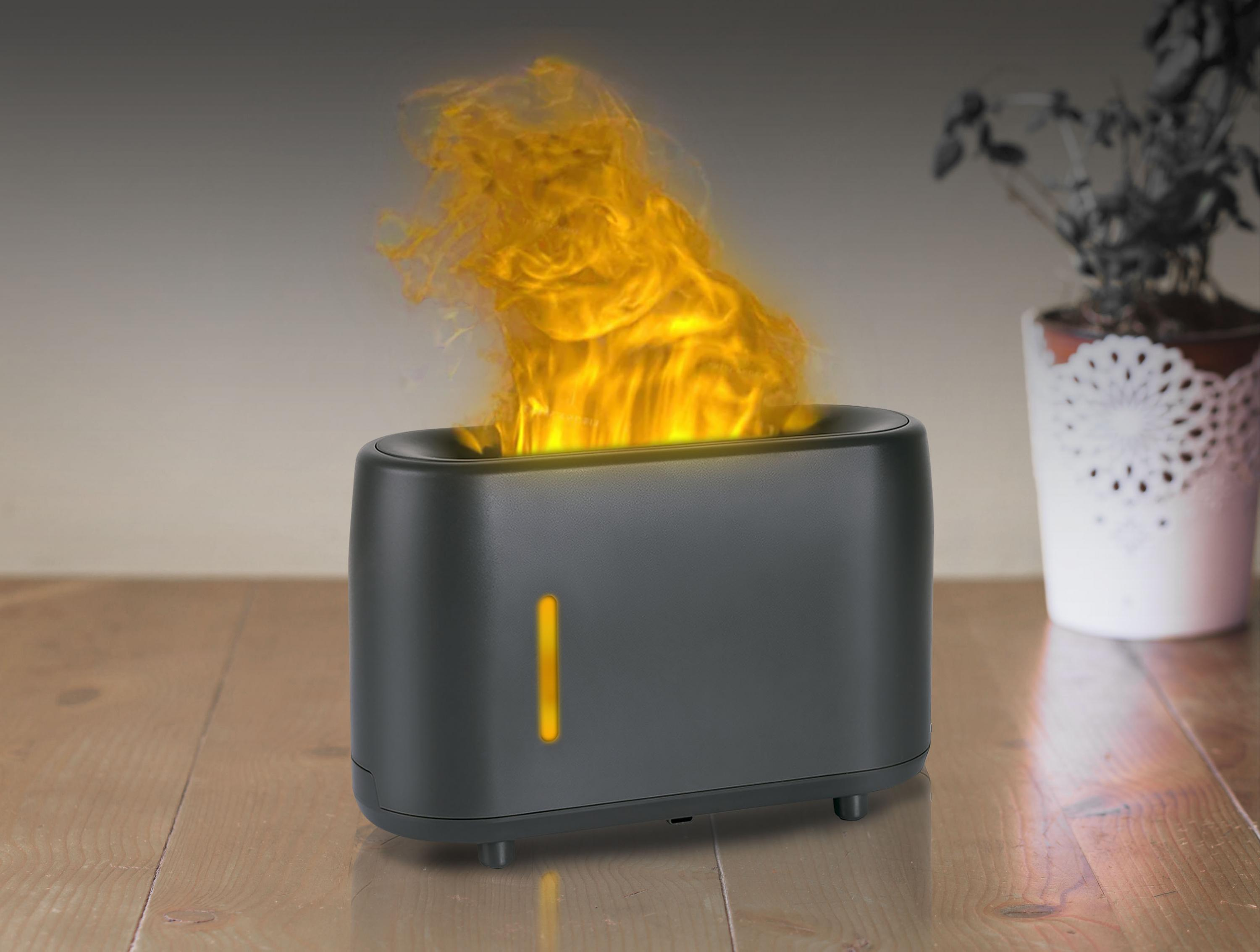 Ein schwarzes Gerät mit Flammeneffekt und gelber Flamme, das auf Holz steht.