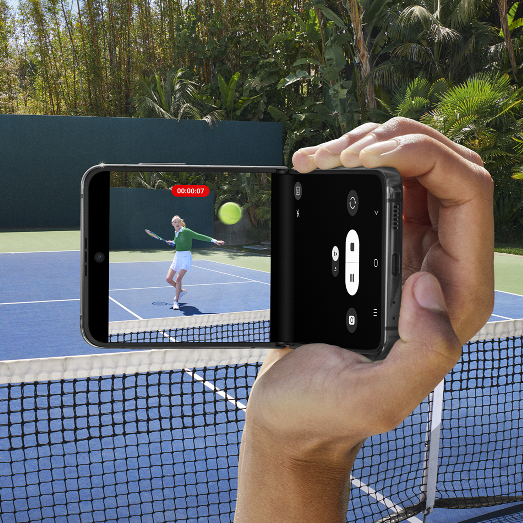 Una mano sosteniendo un teléfono que muestra un partido de tenis con una red y una cancha azul al fondo.