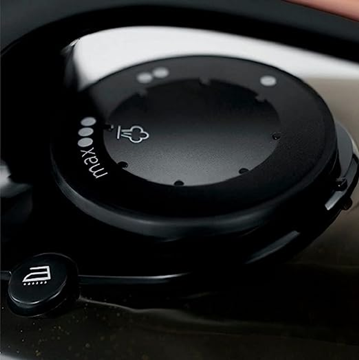 Zbliżenie czarnego żelazka, pokazujące pokrętło sterowania z ustawieniami pary.