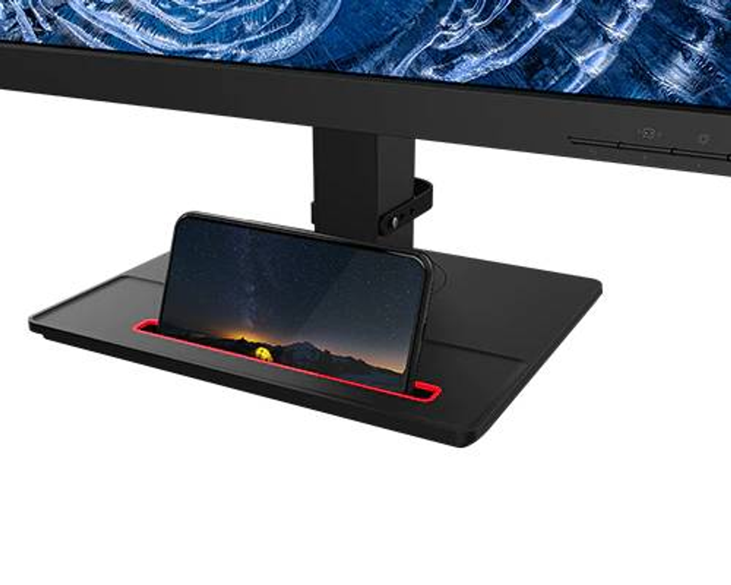 Ein Smartphone in einer Ablage unter einem Monitor. Das Telefon zeigt eine Landschaft mit rotem Rand.