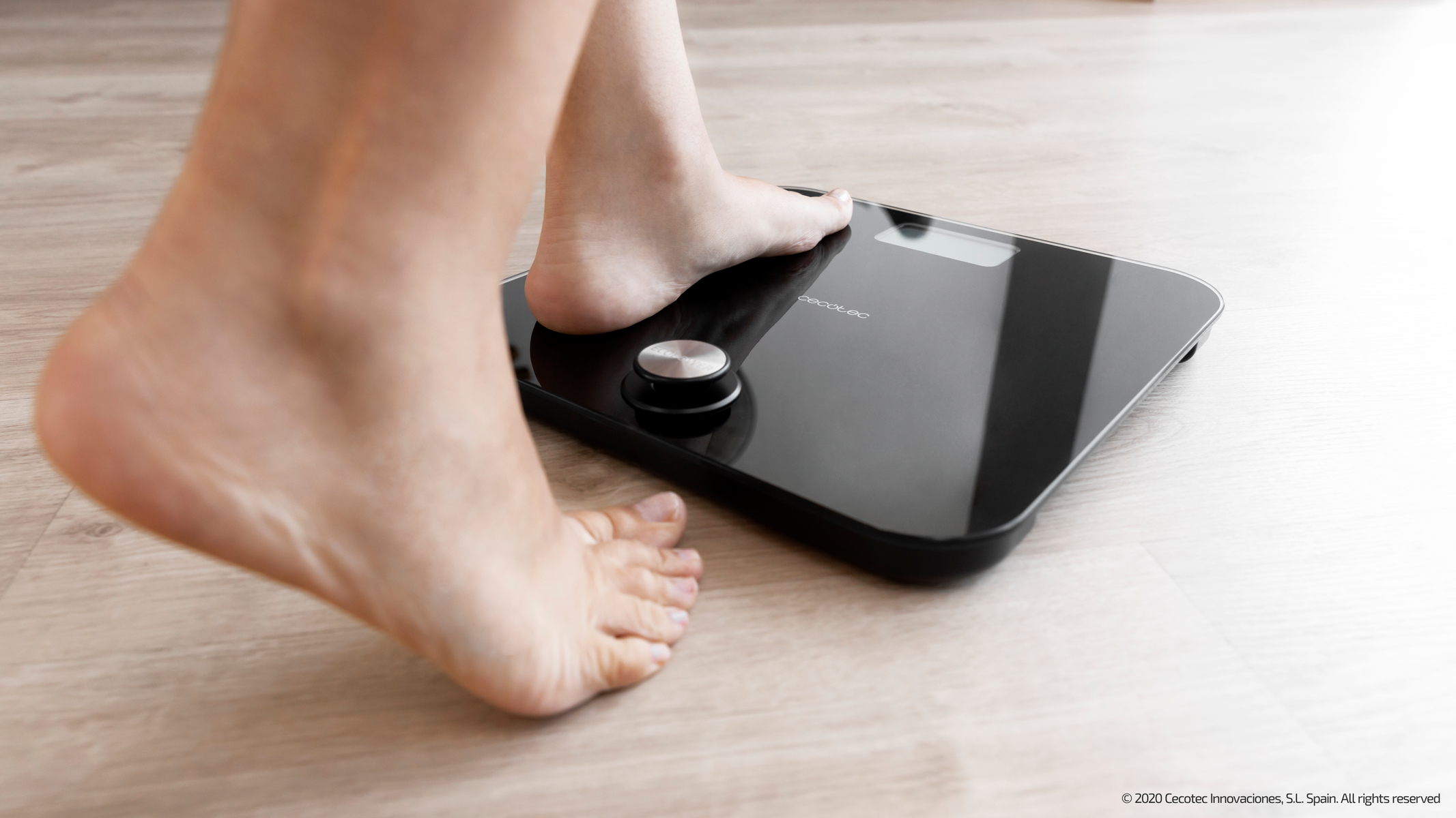 Bose stopy na czarnej wadze cyfrowej na jasnej drewnianej podłodze. Trwa pomiar.