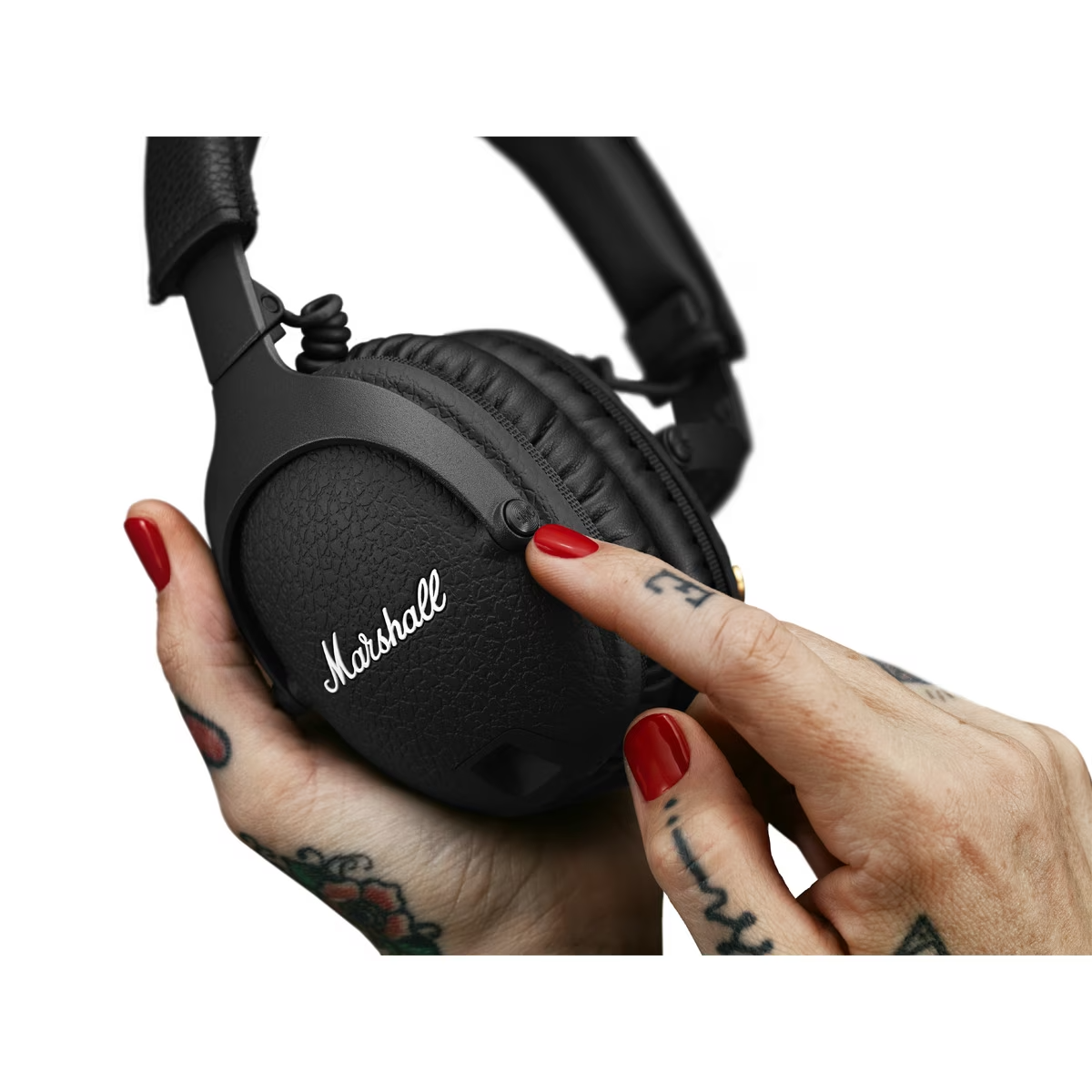 Una mano con esmalte de uñas rojo presionando un botón en un auricular Marshall negro.