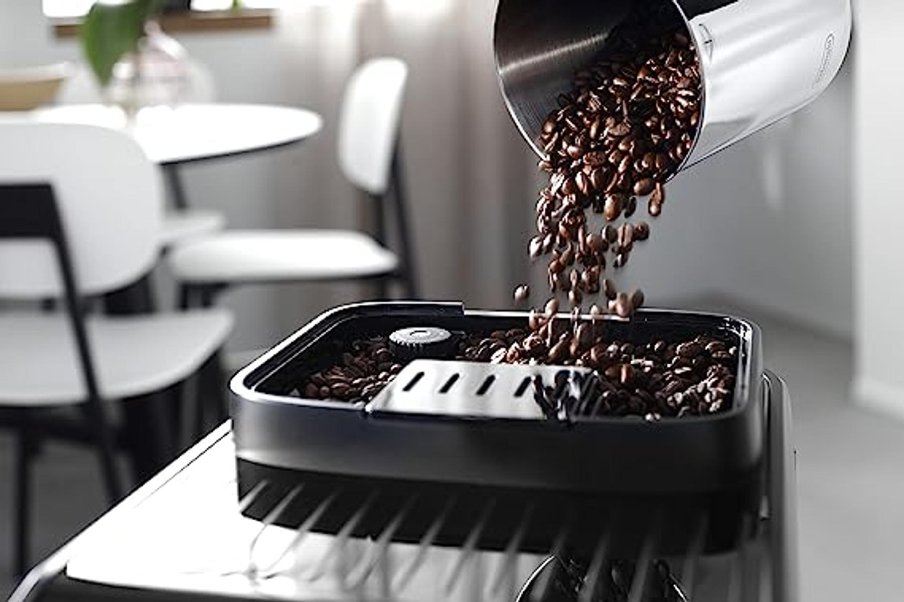 Chicchi di caffè versati da un contenitore in una macchina da caffè.