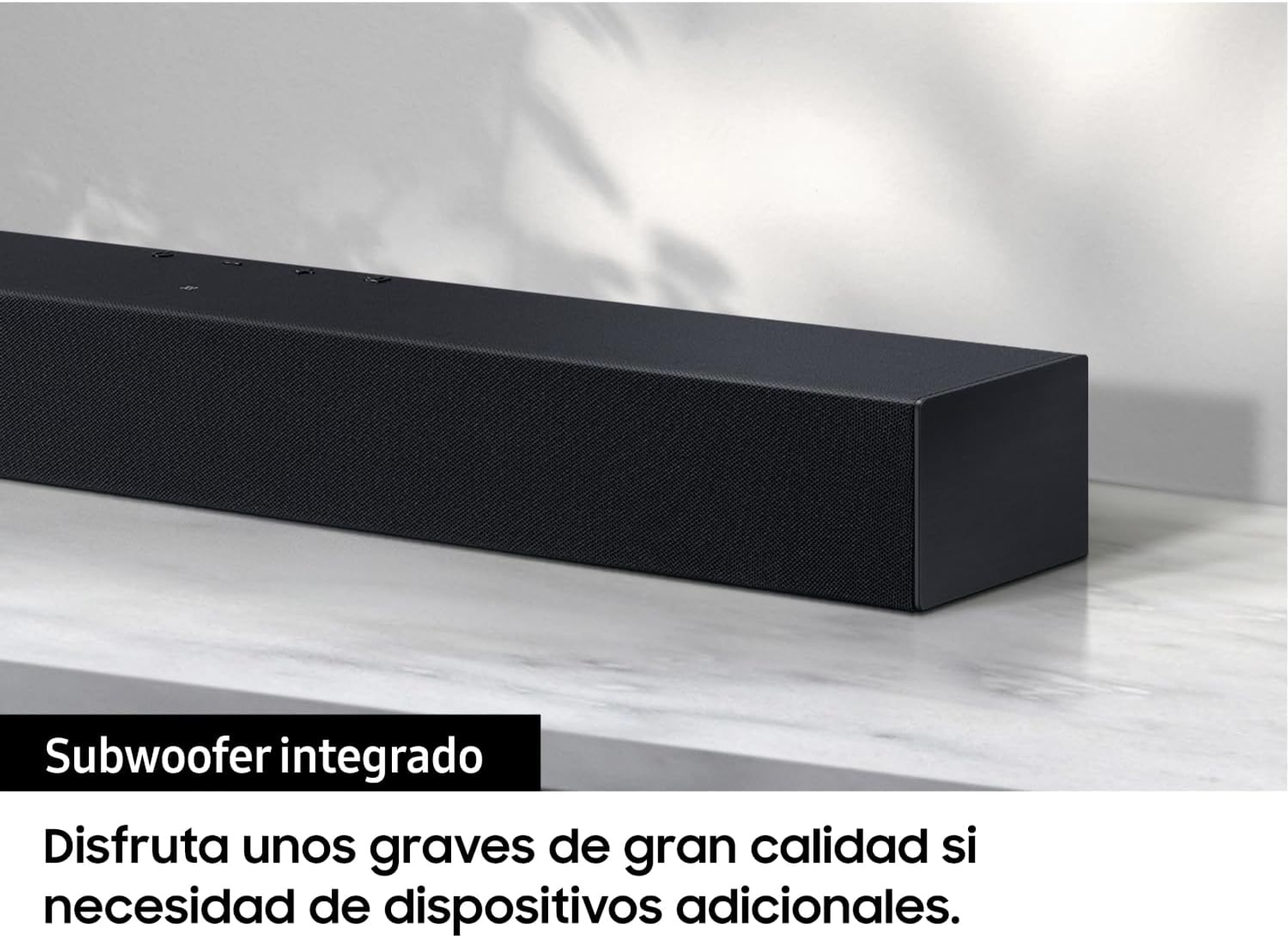 Czarny soundbar na białej powierzchni; tekst: "Zintegrowany subwoofer".