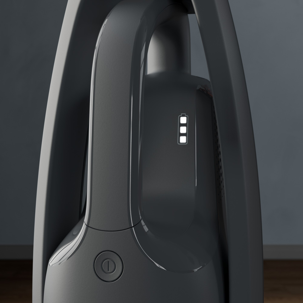 Nahaufnahme eines dunkelgrauen Staubsaugergriffs mit drei weißen Lichtern, die den Batteriestand anzeigen.