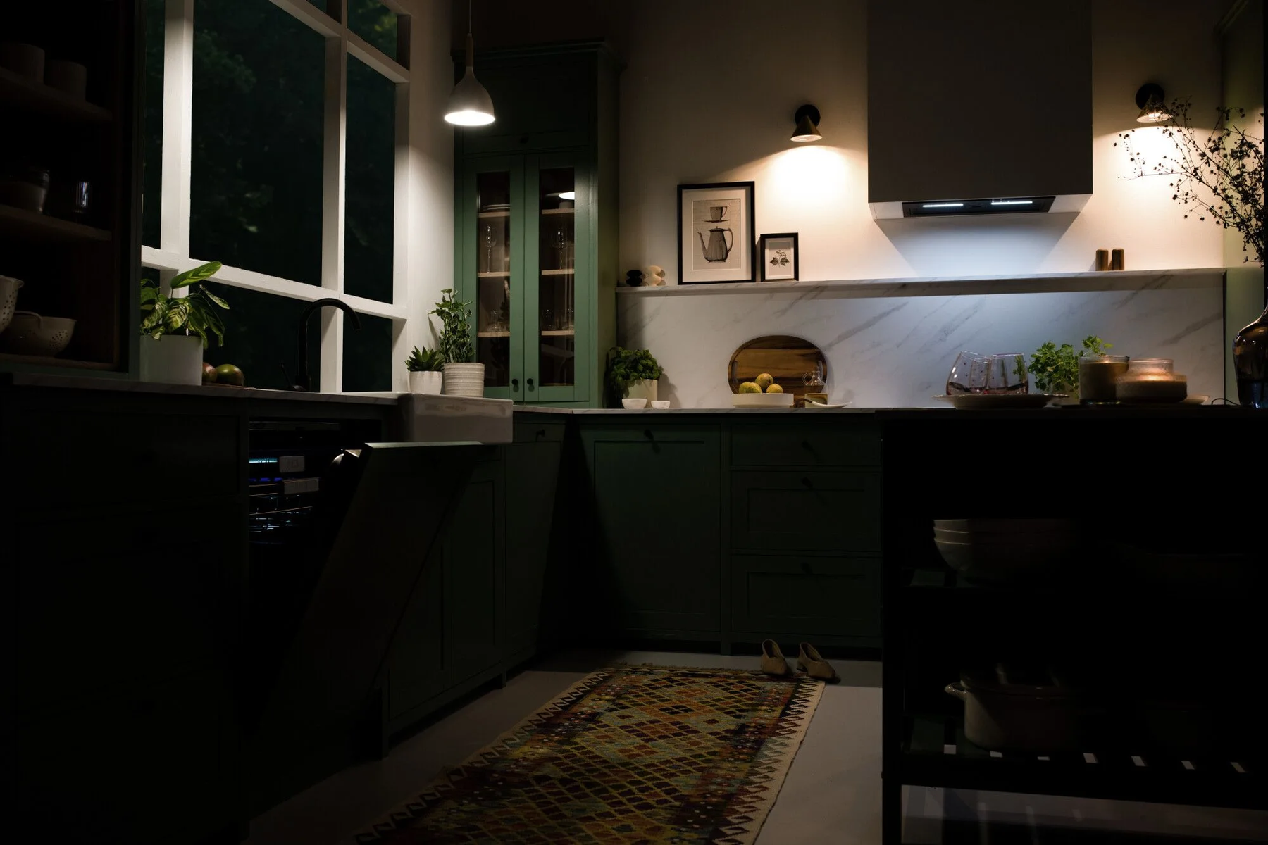 Cocina con gabinetes verde oscuro, encimeras blancas y una ventana.