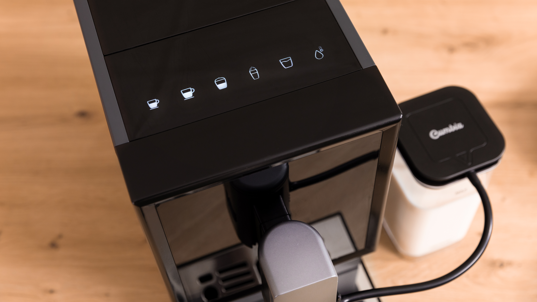 Schwarze Kaffeemaschine mit beleuchteten Symbolen oben und einem kleinen Behälter.
