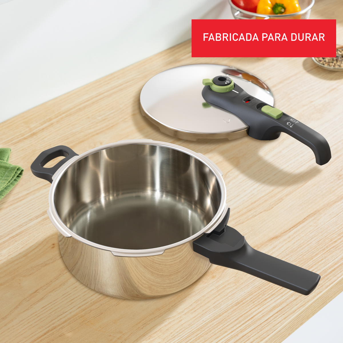 Una olla a presión plateada con asa y tapa negras sobre una mesa de madera.