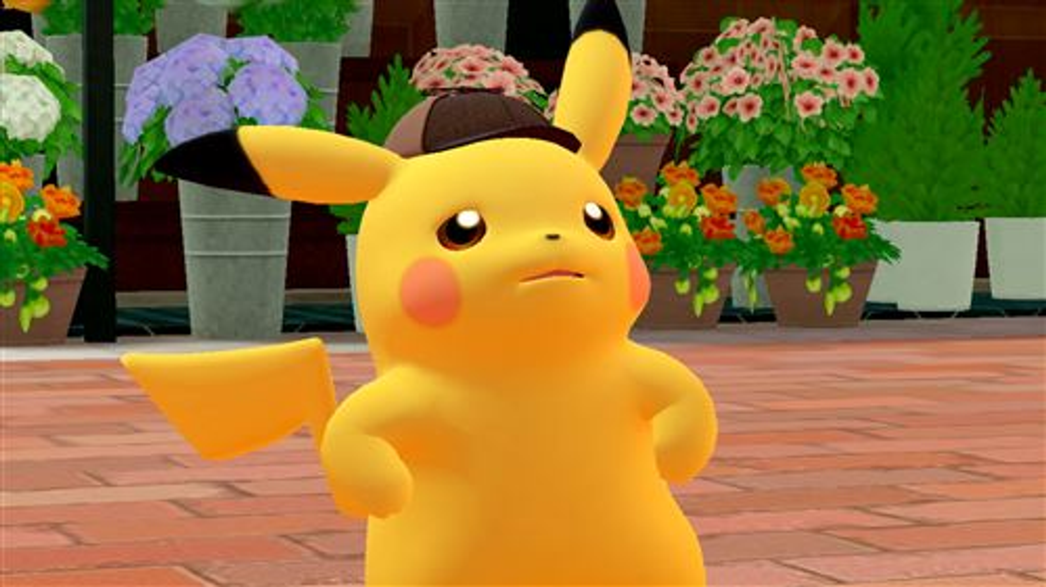 Pikachu con sombrero, de pie en un camino de ladrillos con flores detrás.