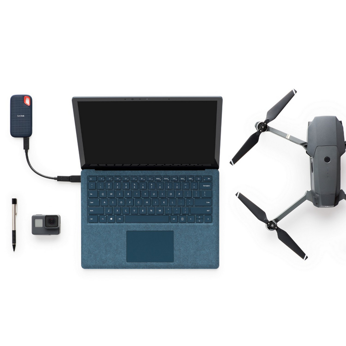 Laptop, Drohne, Kamera und externe Festplatte auf weißem Untergrund.