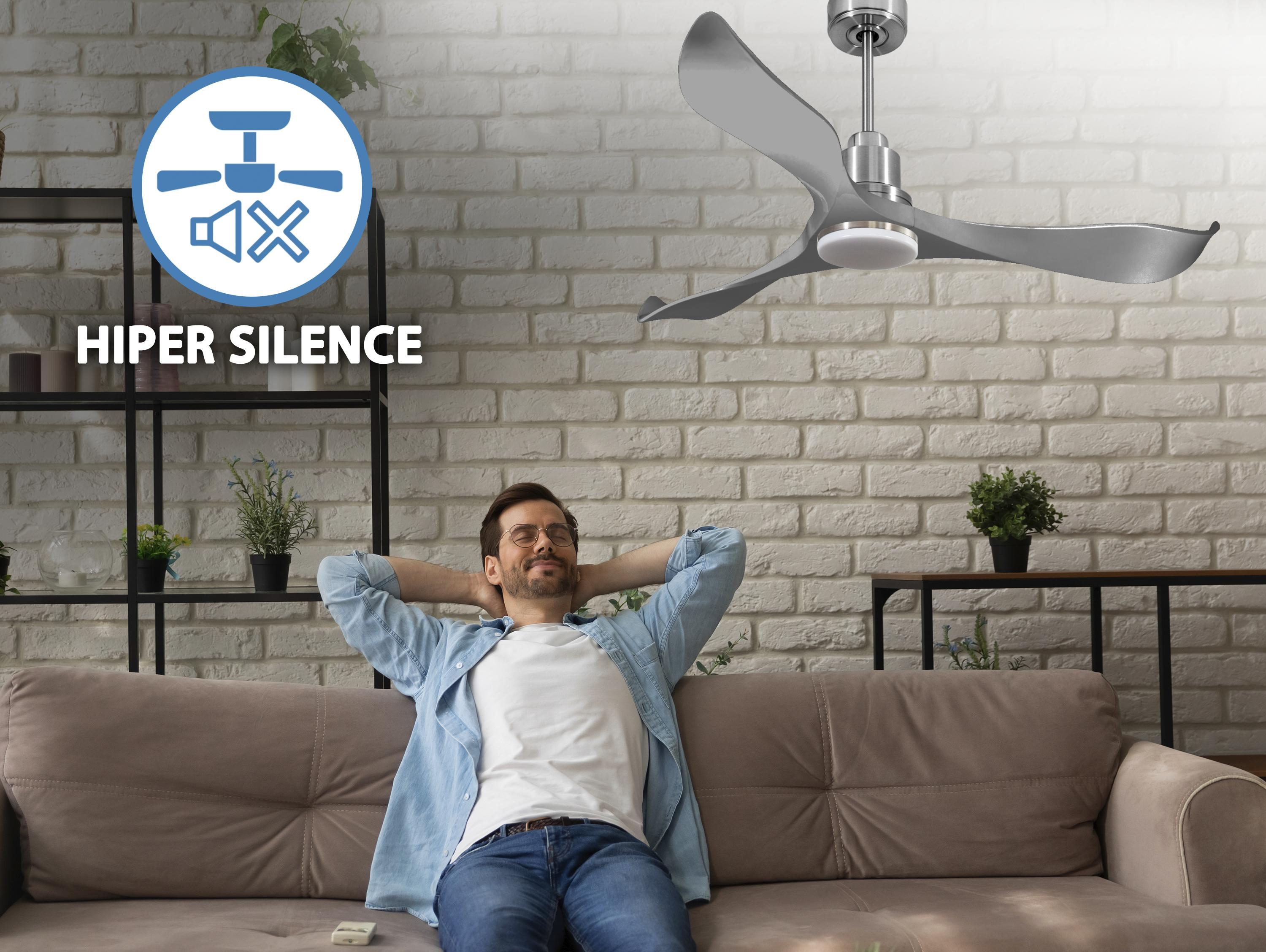 Hombre relajándose en sofá con ventilador de techo. Texto "Hiper Silence" y símbolo visibles.