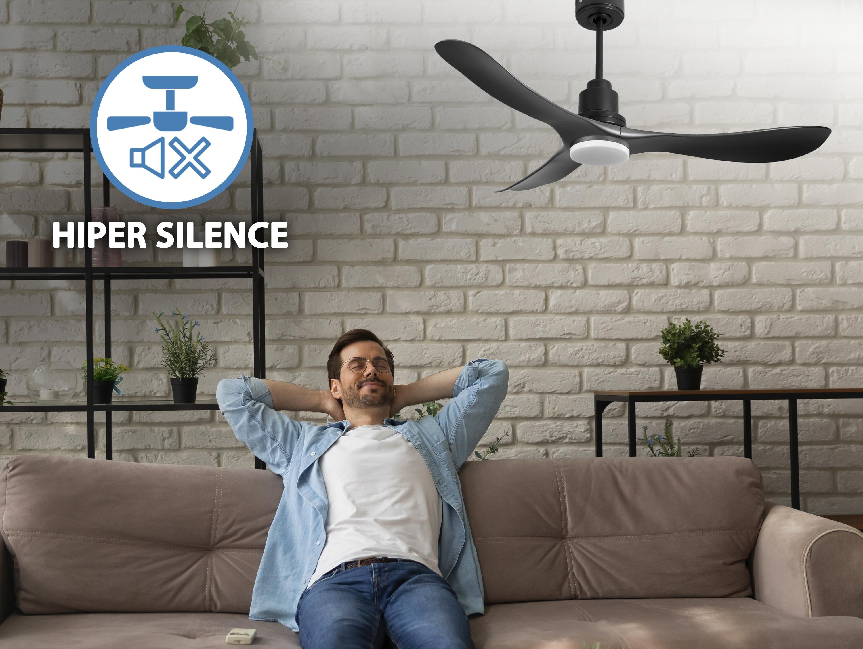 Hombre relajándose en un sofá bajo un ventilador negro. Texto: 'HIPER SILENCIO' e icono de ventilador con altavoz tachado.