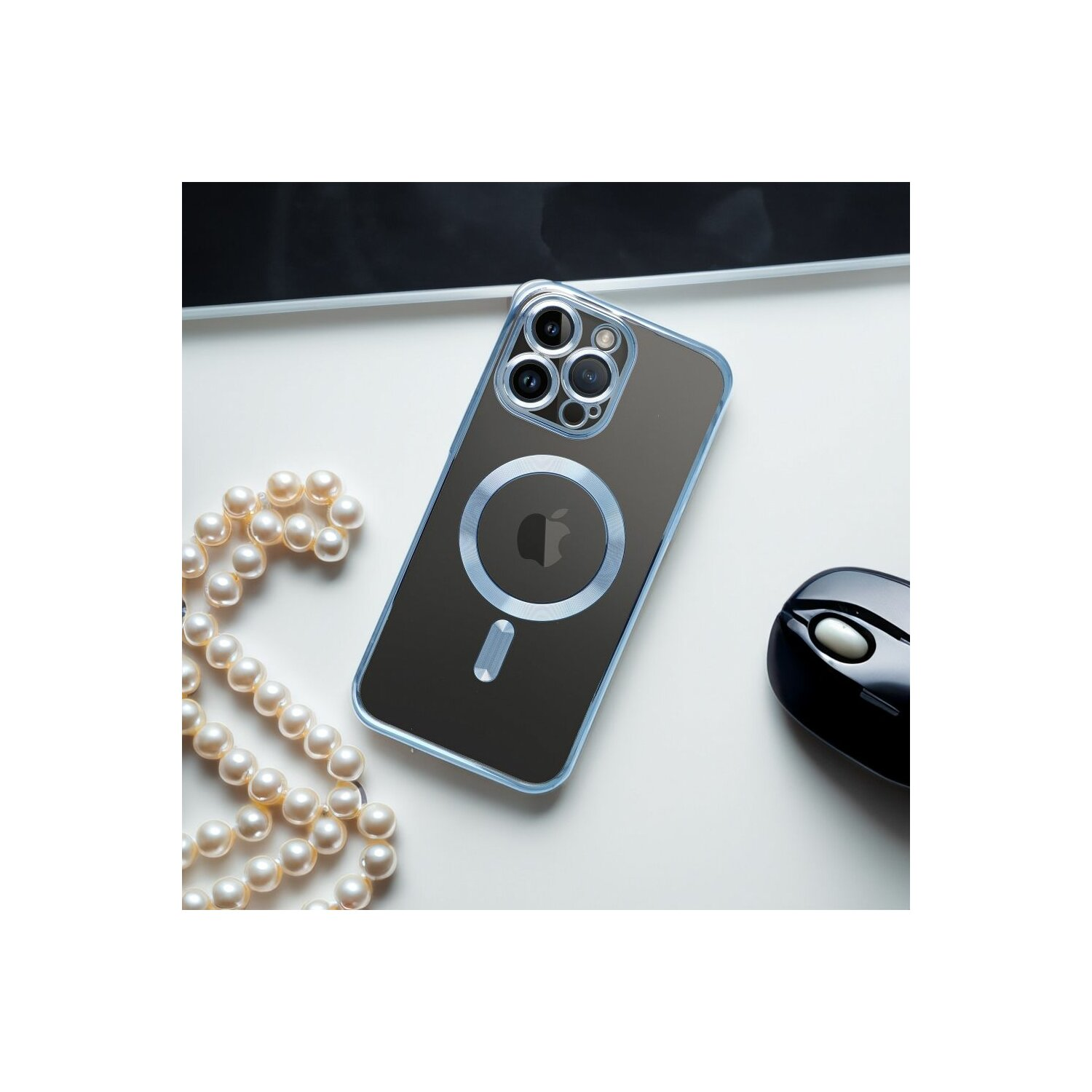 Un iPhone con una custodia trasparente e una collana di perle sono su una superficie bianca, con un mouse nero.