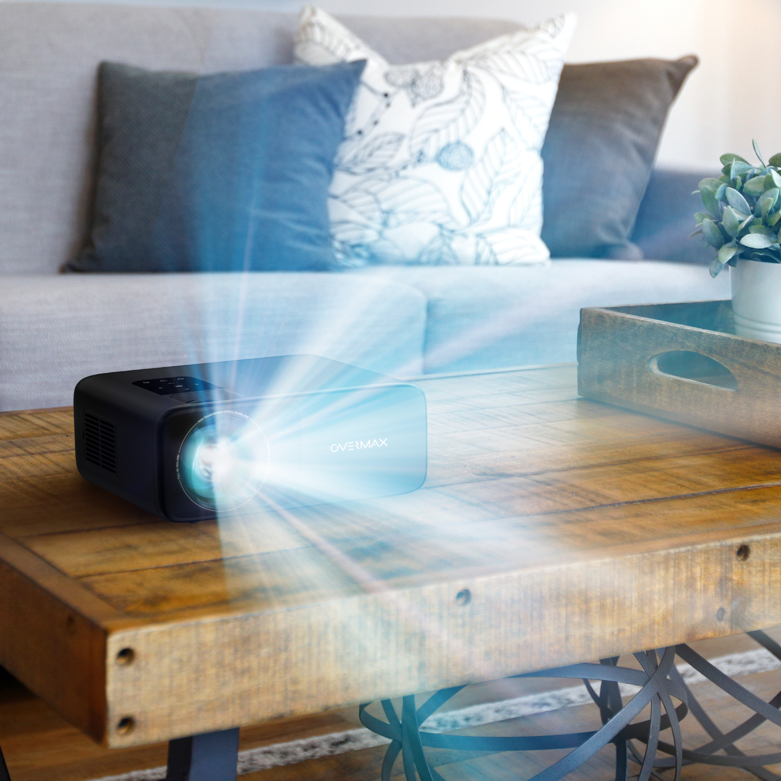 Ein Projektor, der ein helles Bild auf einen Tisch projiziert, mit einem Sofa im Hintergrund.