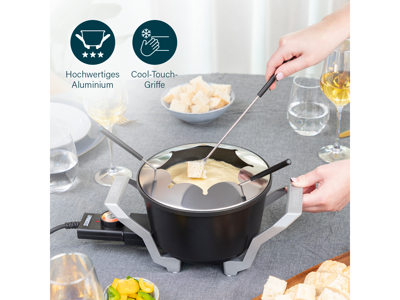 Zestaw do fondue z jedzeniem dookoła. Ludzie go używają, z garnkiem, widelcami i chlebem.