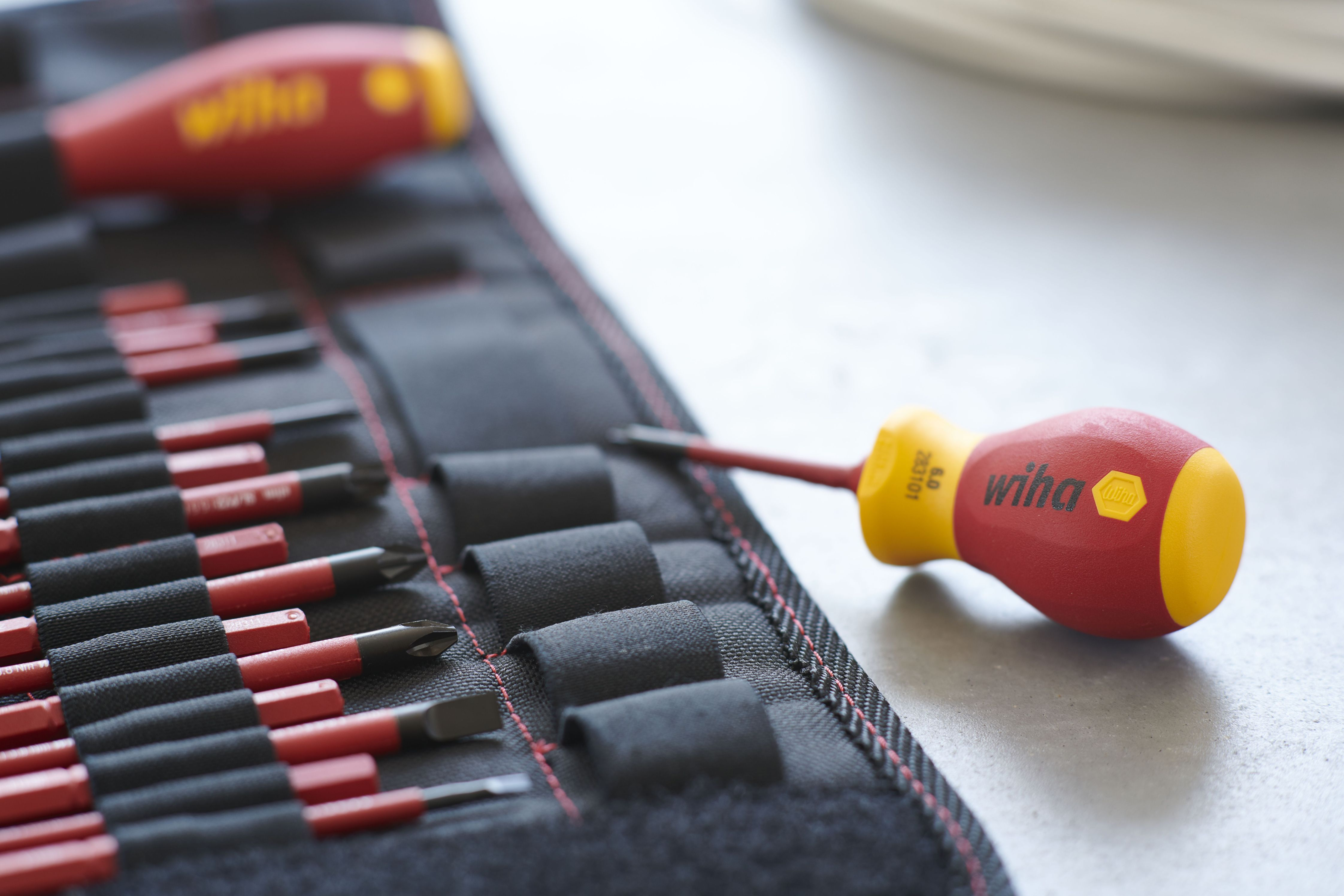 Zbliżenie śrubokrętów w rolce narzędziowej. Czerwone i żółte uchwyty, czarne i czerwone narzędzia.