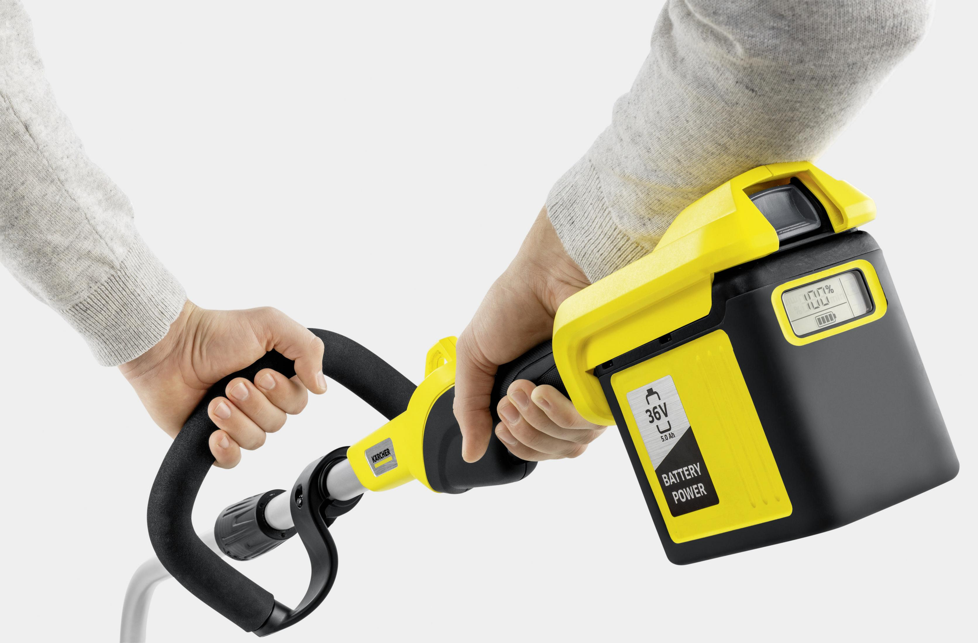 Eine Person hält einen gelb-schwarzen Akku-Rasentrimmer mit Batteriestatusanzeige.