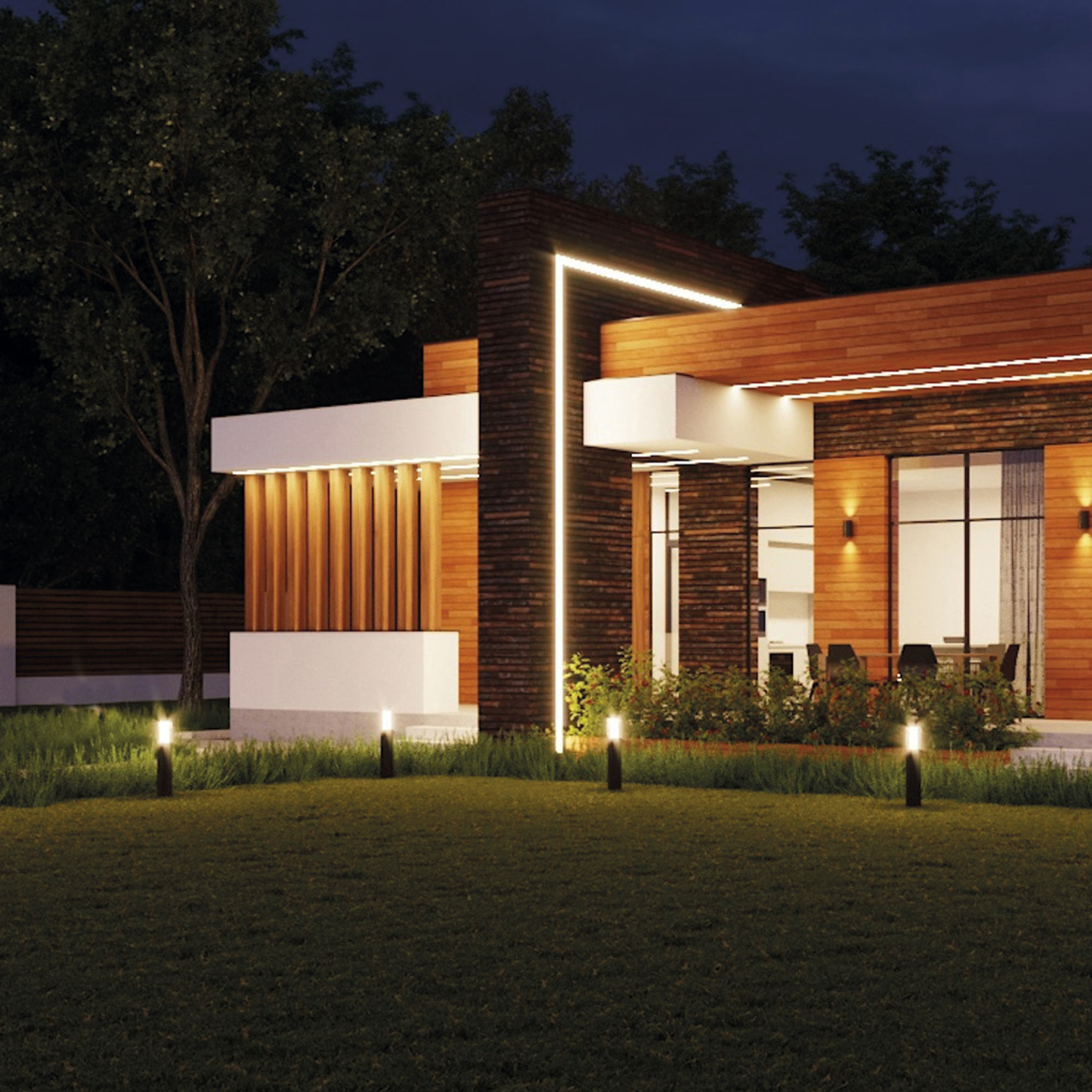 Casa moderna de noche, con luces que iluminan el paisaje. Árboles y césped en primer plano.