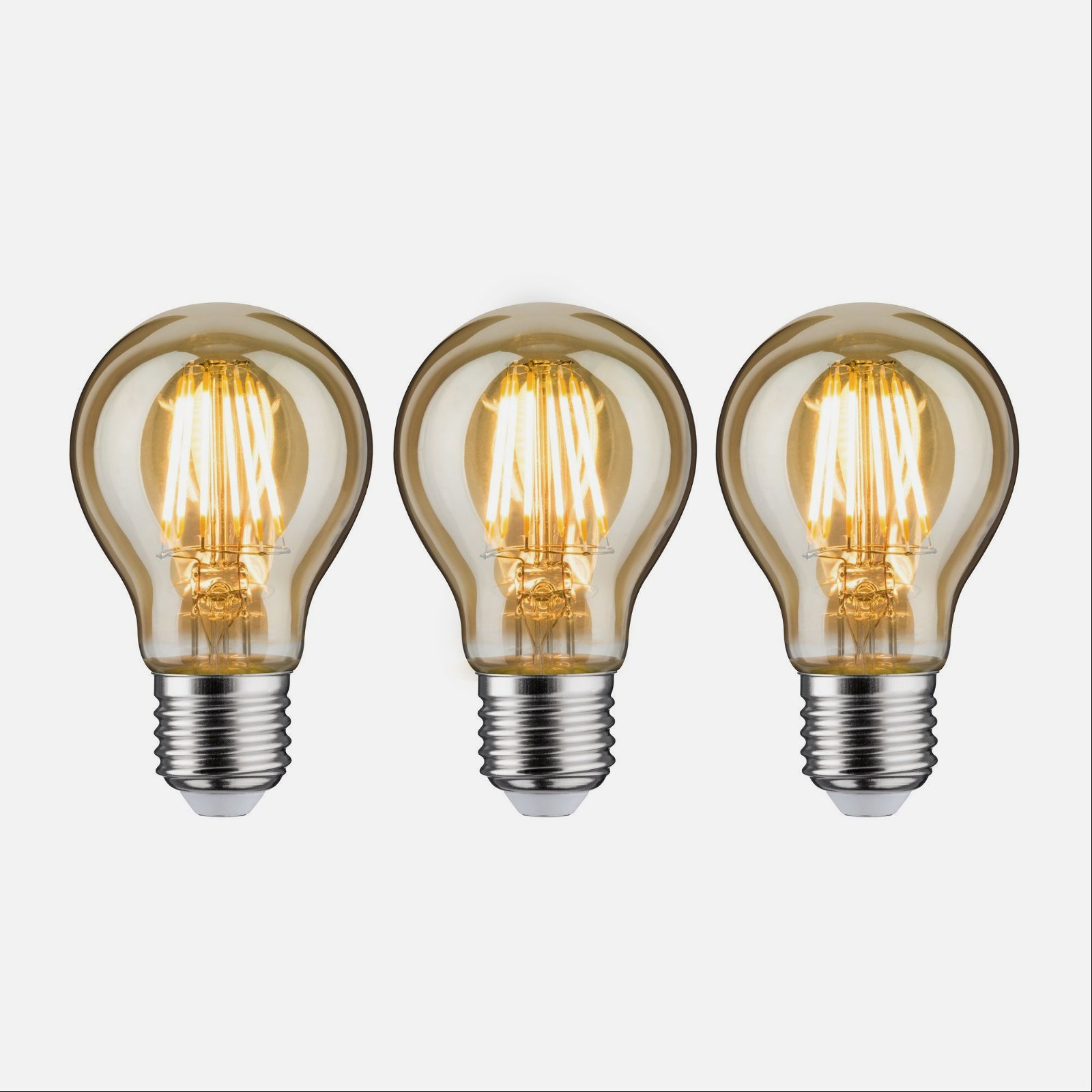 Trzy żarówki ze złotym żarnikiem. Białe tło.