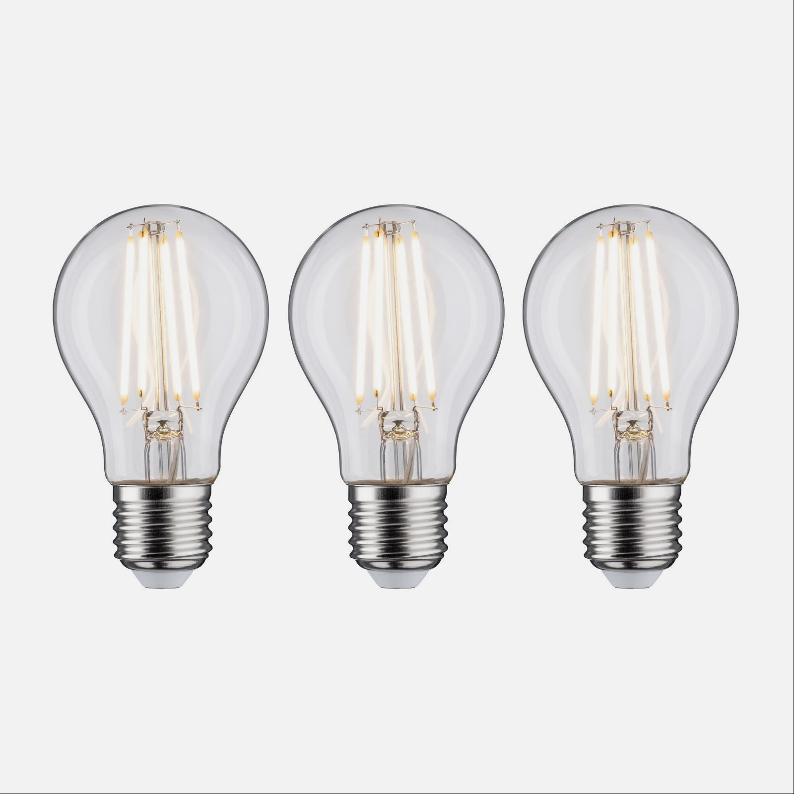 Trzy przezroczyste żarówki ze srebrną podstawą i widocznymi włóknami, zapalone.