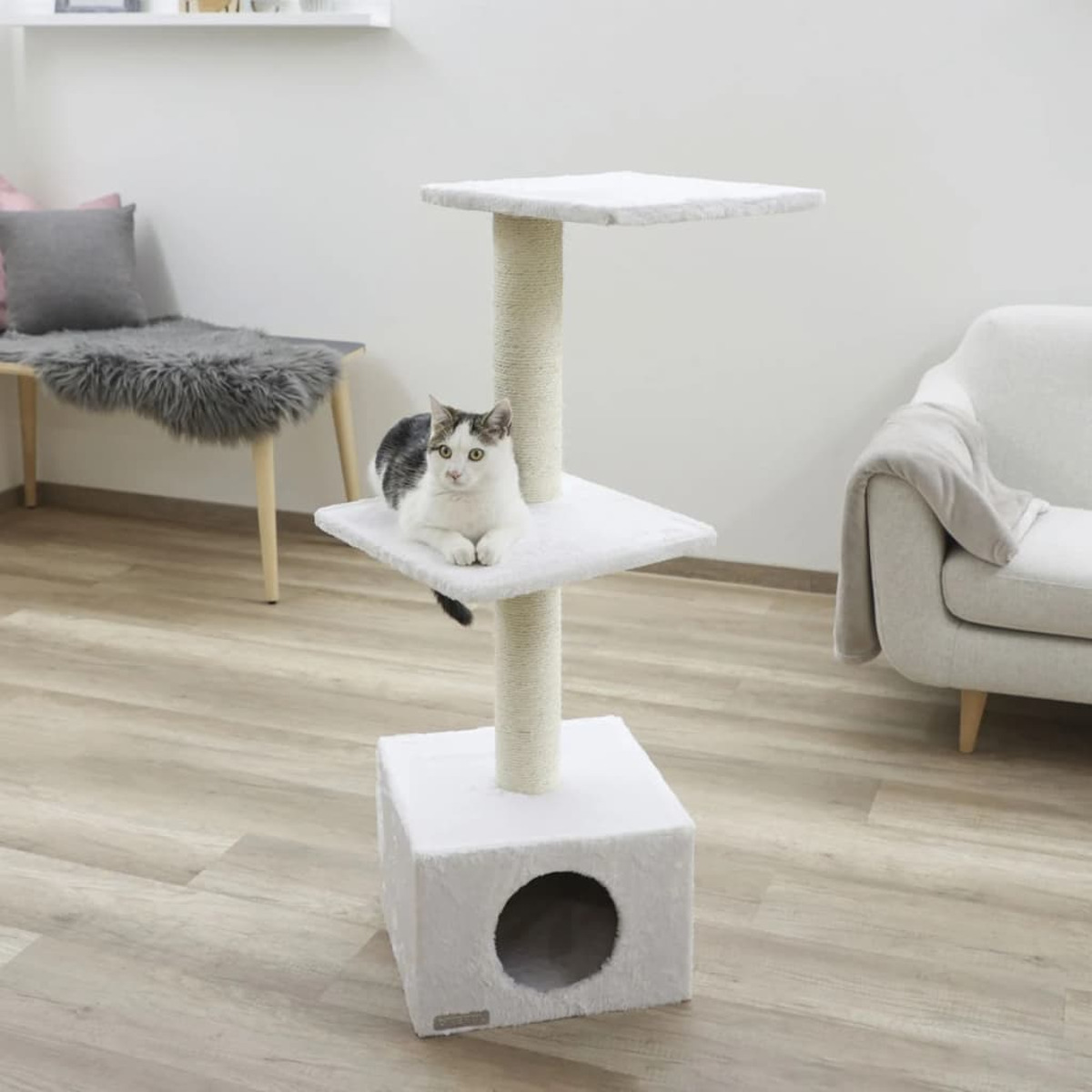 Kratzbaum mit Katze, die sich darauf ausruht. Der Baum ist weiß und hat eine Höhle.
