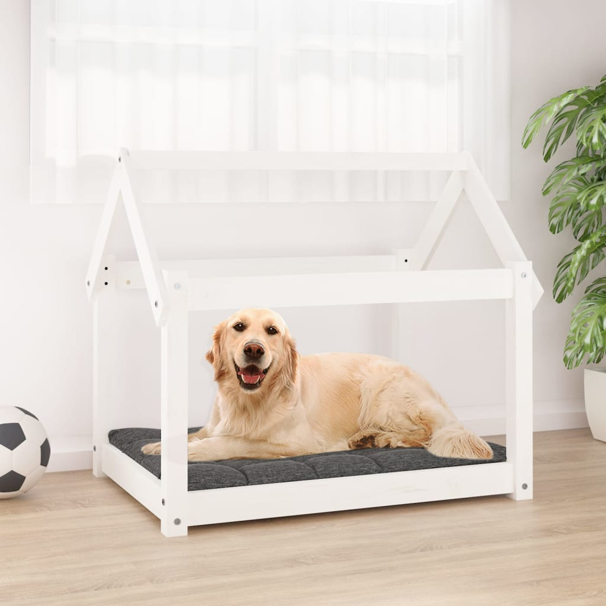 Ein Hund liegt in einem weißen Hundehäuschenbett mit einem grauen Kissen.