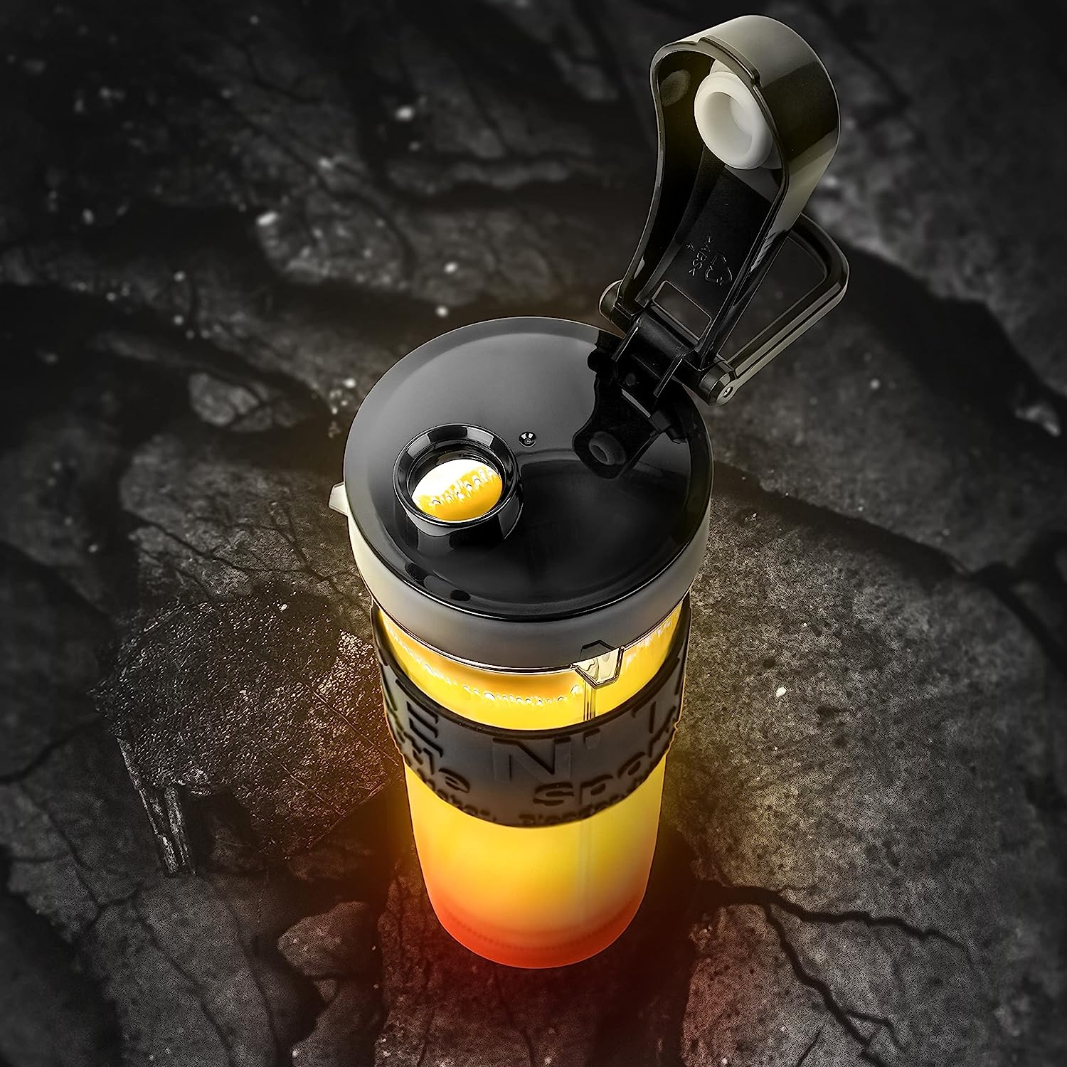 Eine schwarze und gelbe Sportflasche mit offenem Deckel auf dunkler Oberfläche.