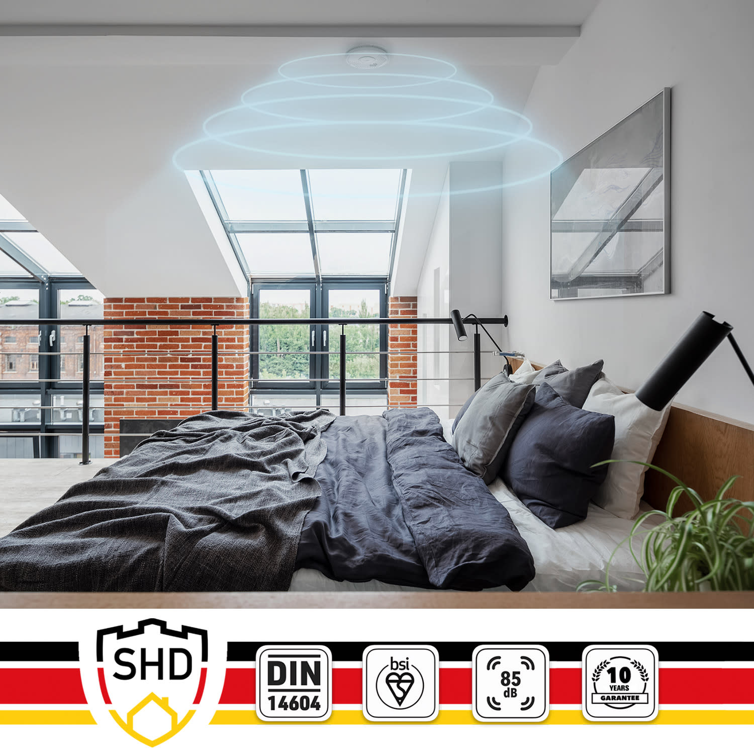 Camera da letto con rilevatore di fumo sul soffitto. Sono visibili un letto e un muro di mattoni.