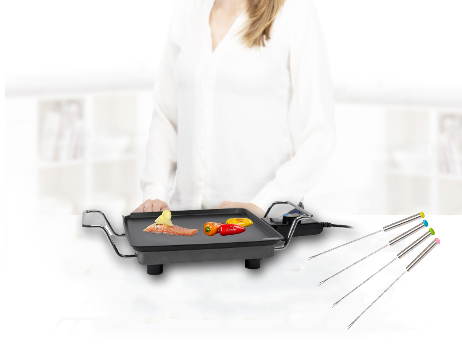 Eine Frau bereitet Essen auf einem schwarzen Elektrogrill zu. Gemüse und Lachs liegen auf dem Grill.