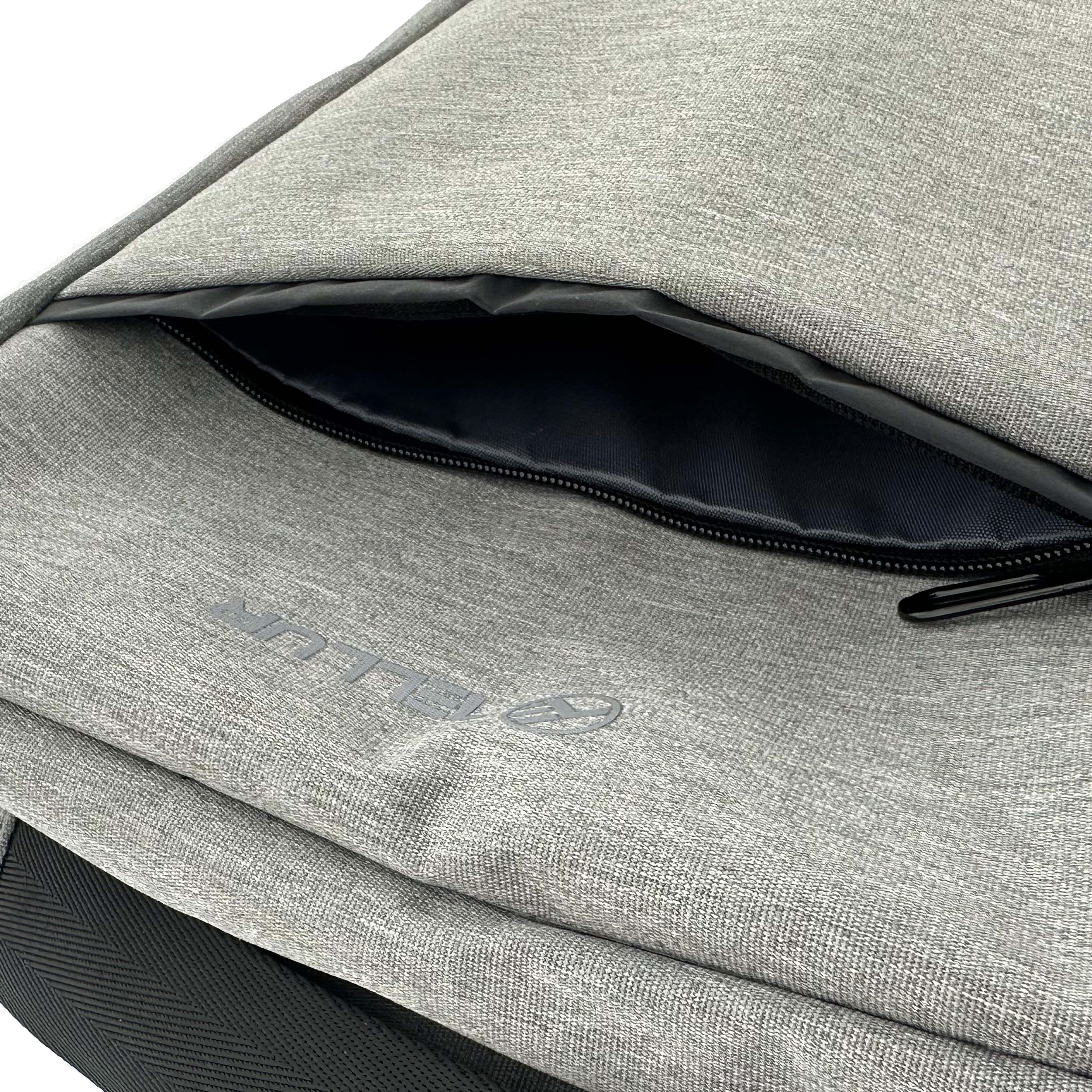 Zbliżenie jasnoszarego plecaka z otwartą kieszenią i czarnym zamkiem błyskawicznym.