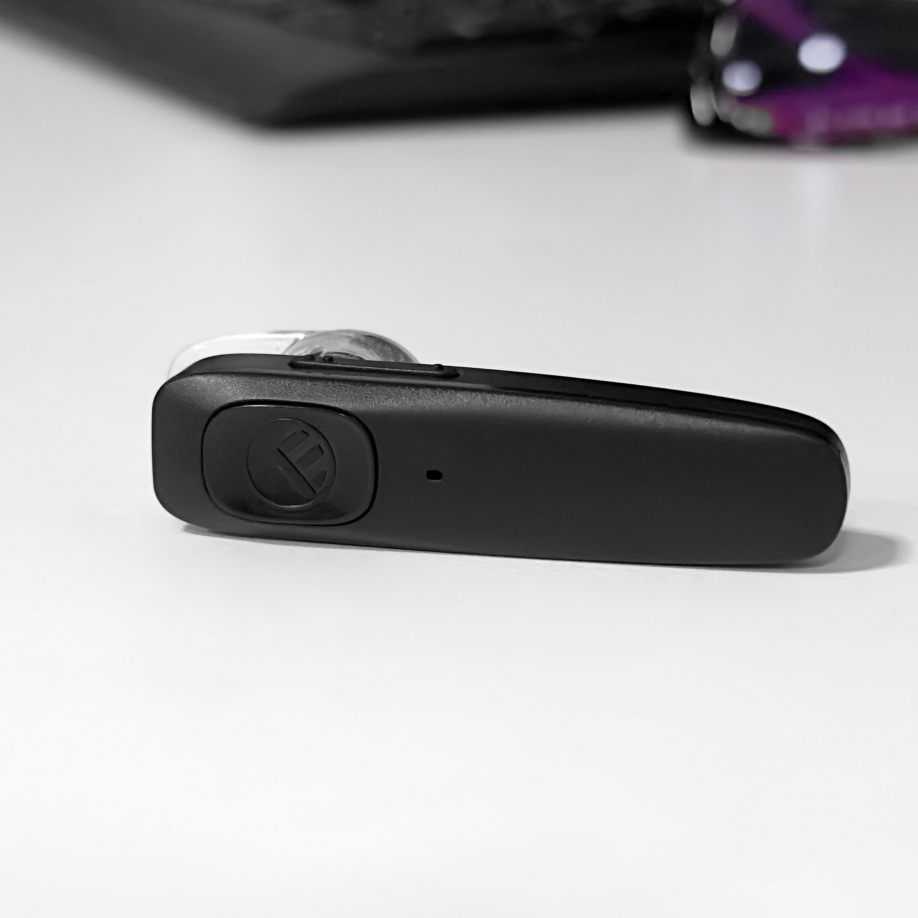 Schwarzes Bluetooth-Headset auf weißer Oberfläche.