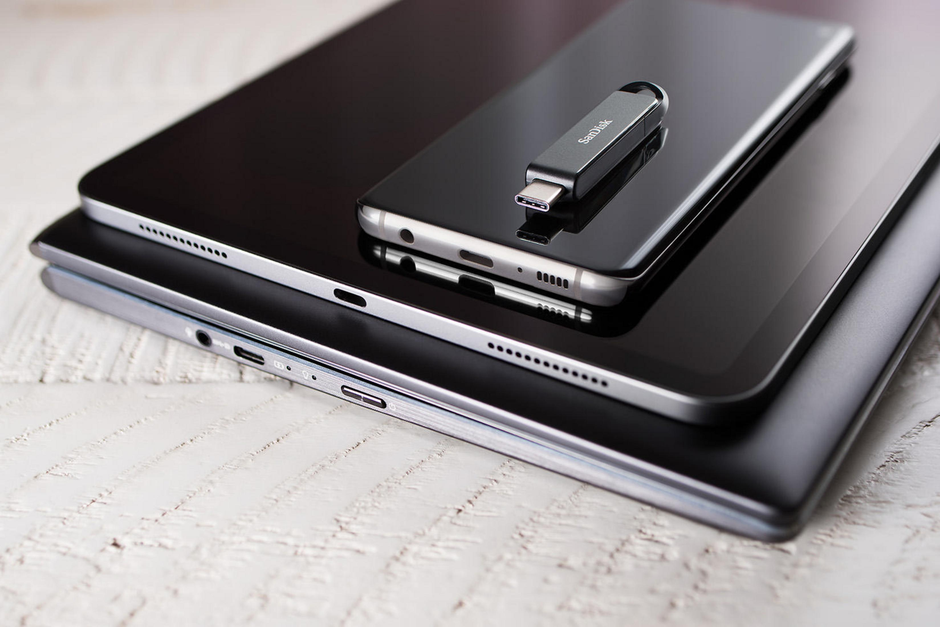 Tablety i telefon z pamięcią flash USB na wierzchu, na białej drewnianej powierzchni.