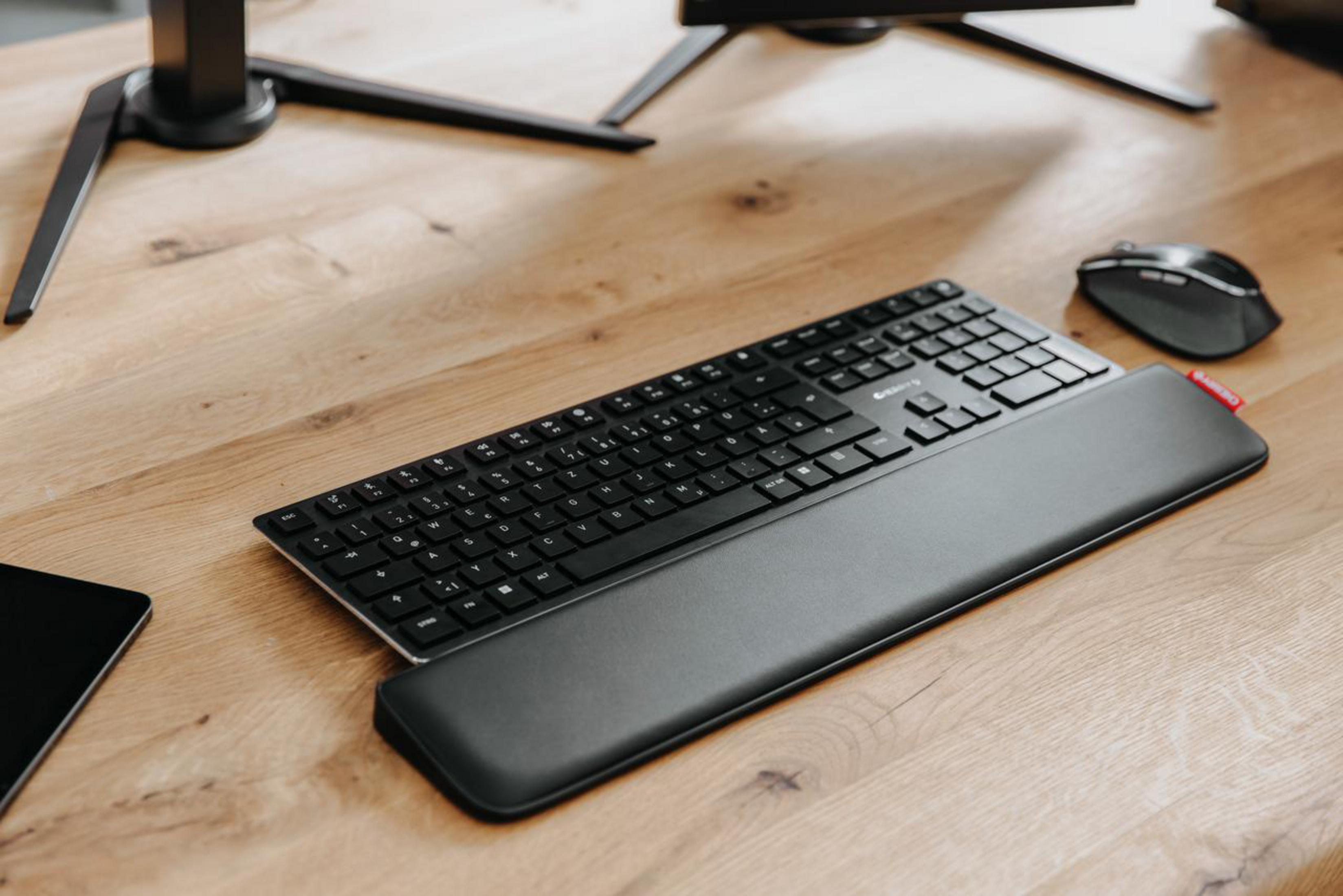 Czarna klawiatura z podpórką pod nadgarstek na drewnianym biurku, z myszą.