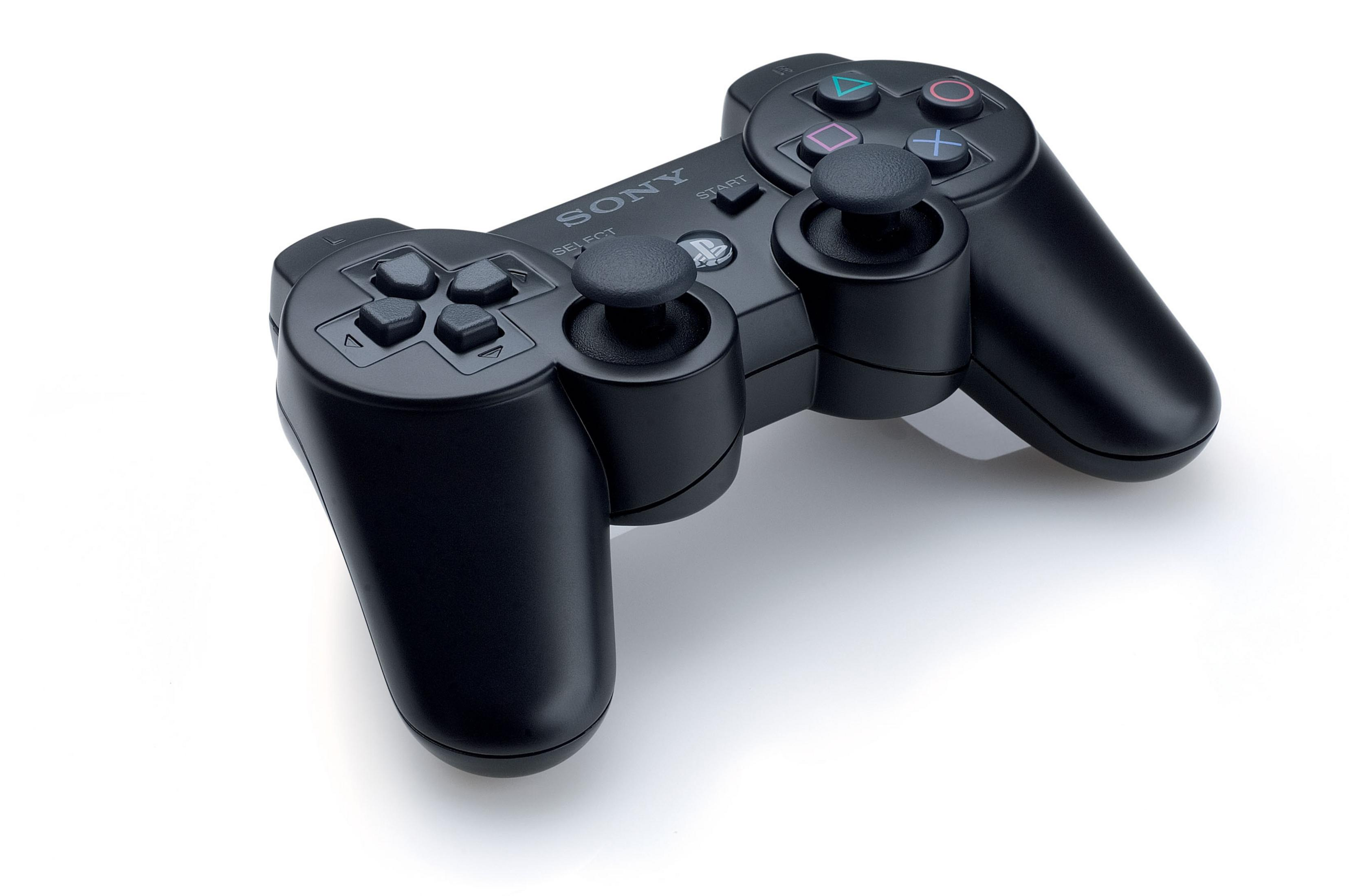 Un controller PlayStation nero su una superficie bianca. Il controller ha pulsanti e levette.