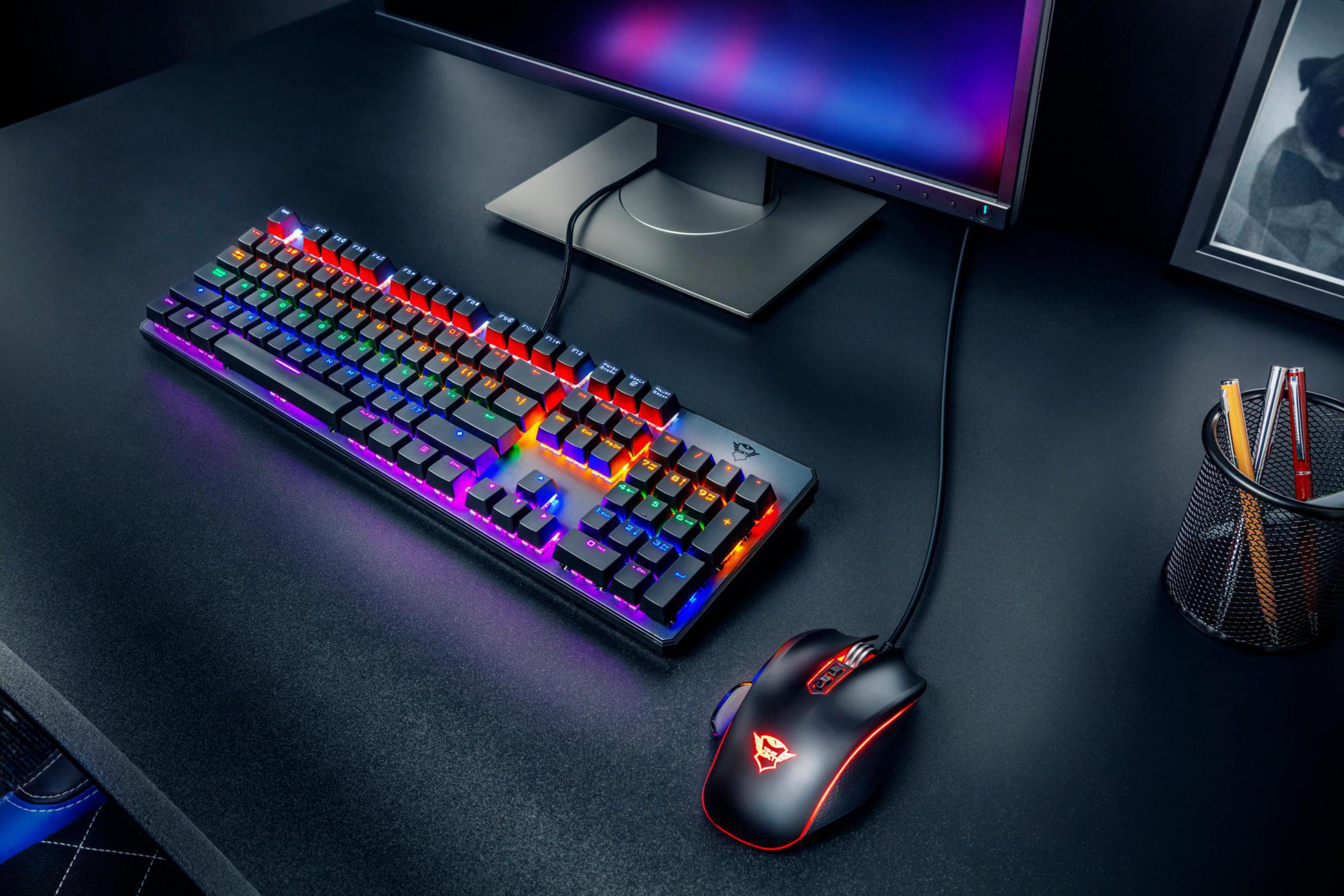 Ein Gaming-Setup: Tastatur, Maus mit roten Akzenten, Monitor und ein Schreibtisch.