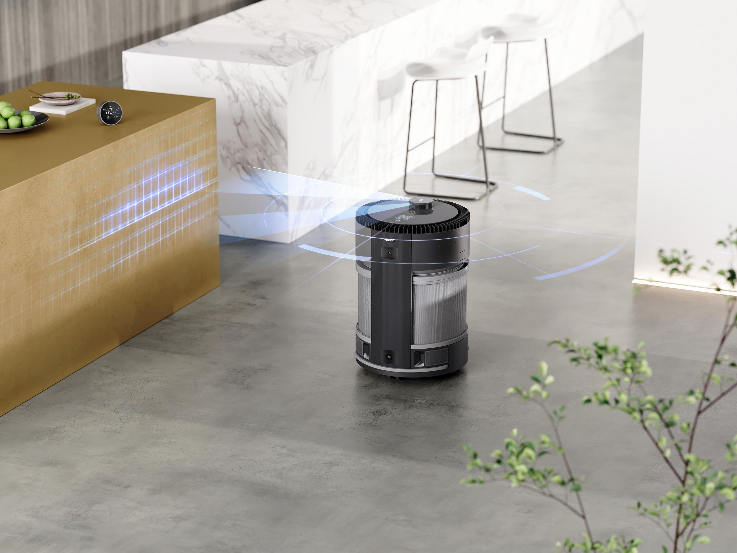 Ein moderner Roboter-Staubsauger auf grauem Boden. Eine goldene Theke und Hocker im Hintergrund.