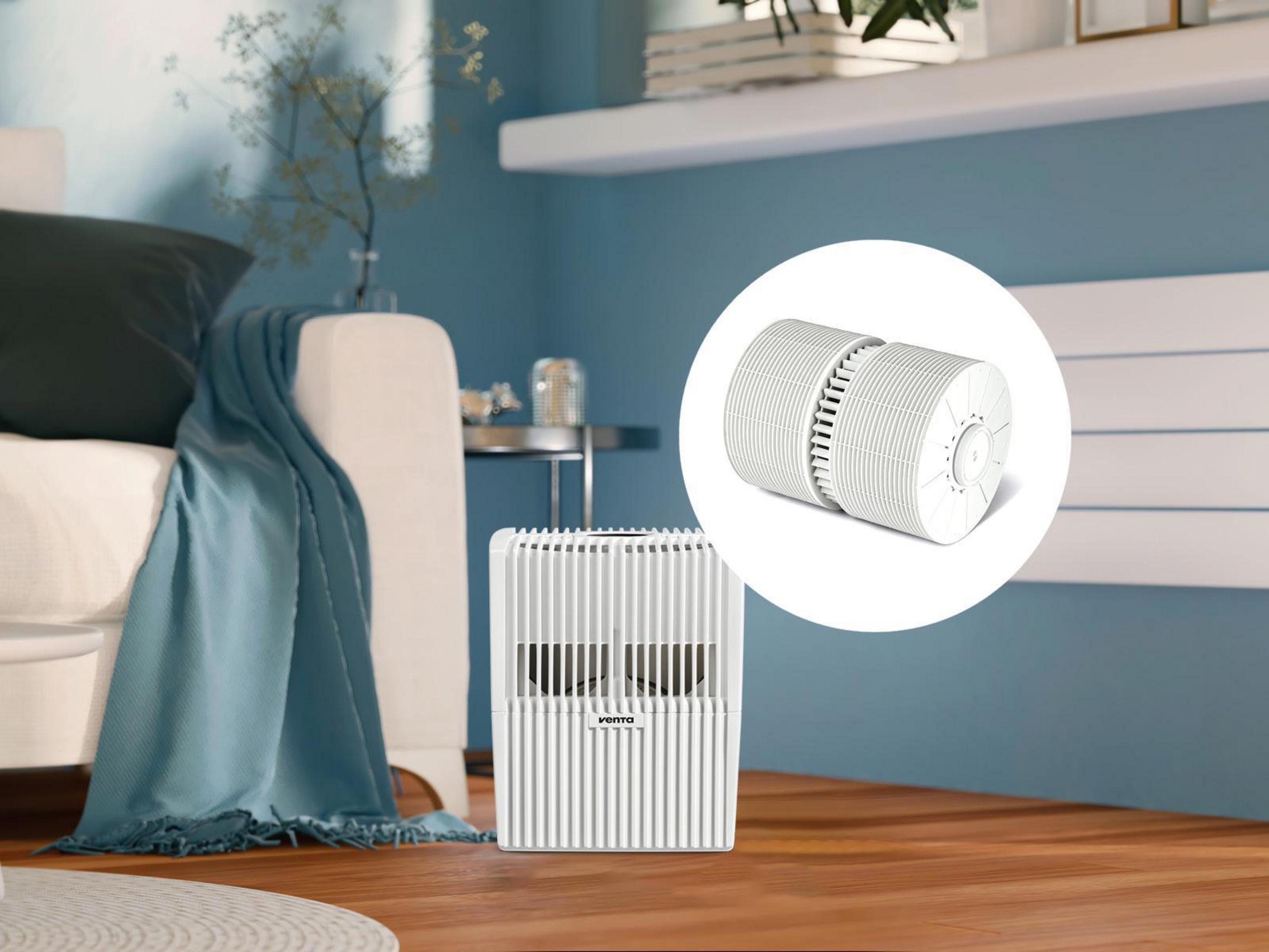 Biały oczyszczacz powietrza z oddzielną częścią, w pokoju z niebieską ścianą.